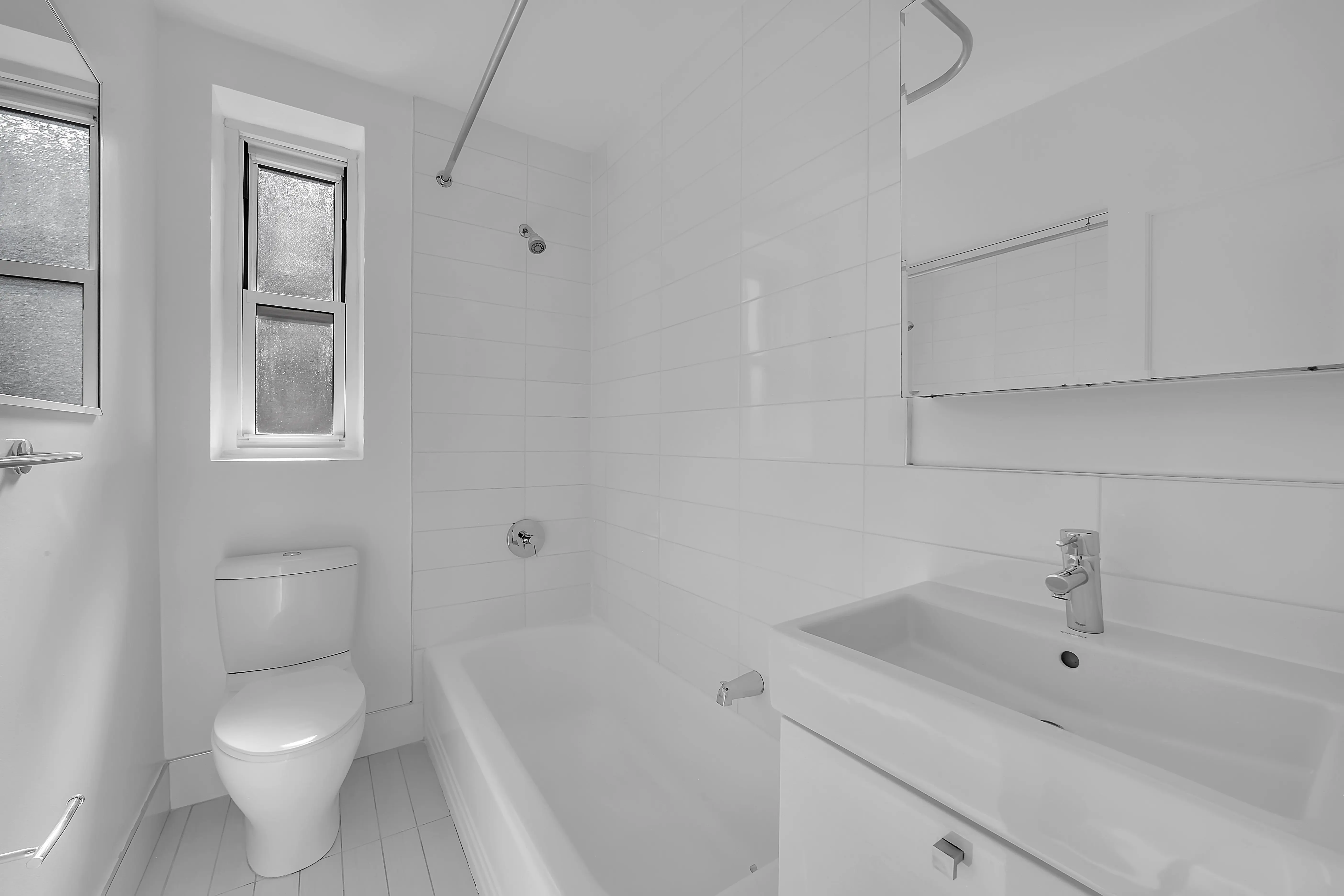 A bright white bathroom showcasing a toilet, sink, and bathtub in a modern design.