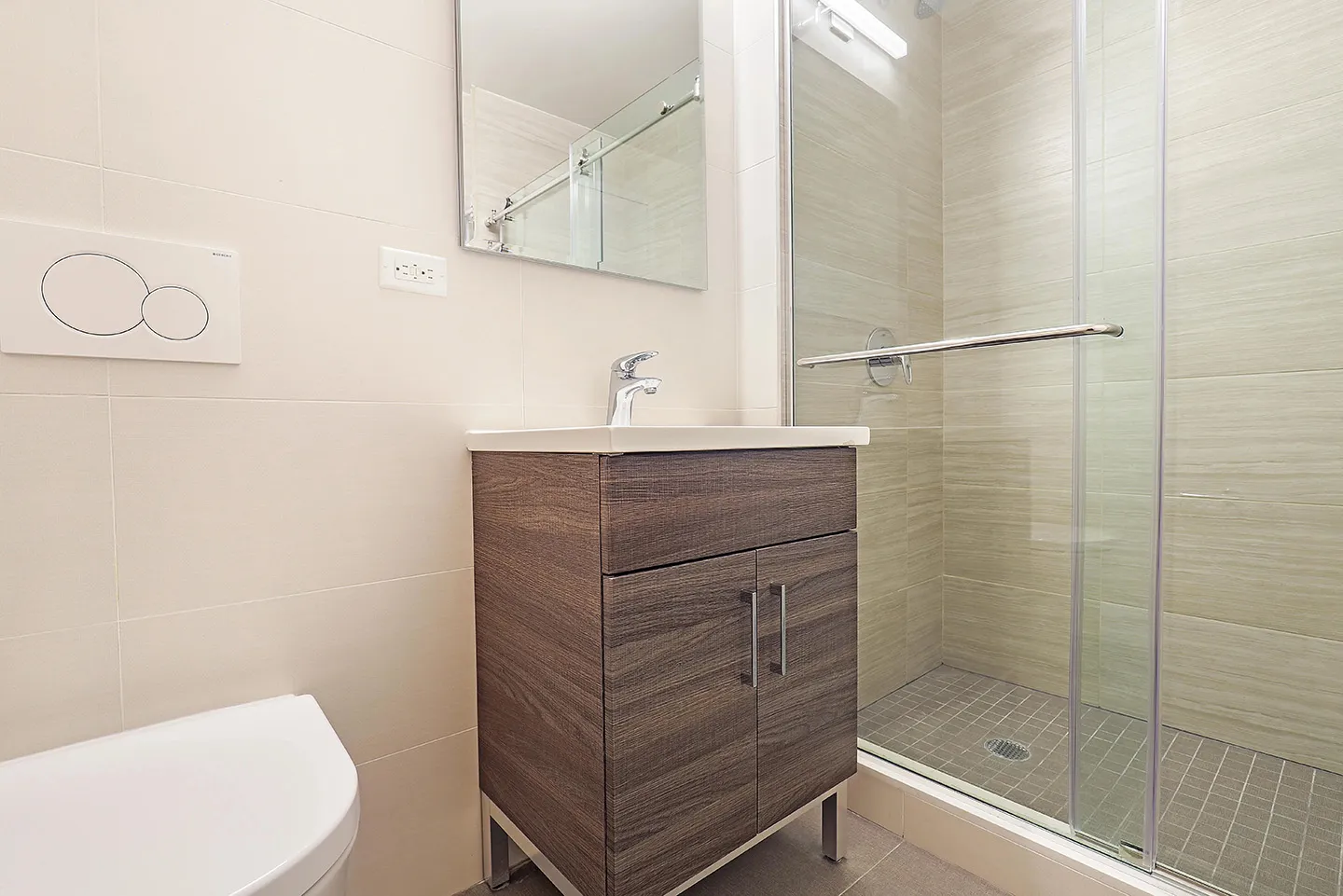 A well-lit bathroom containing a toilet, sink, and shower stall, emphasizing a simple and organized design.