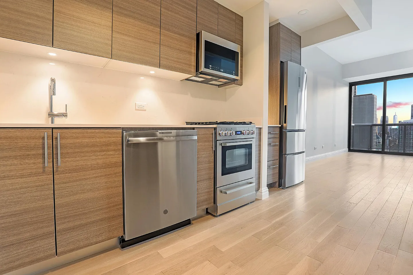 A contemporary kitchen with sleek stainless steel appliances and rich wood flooring, offering a blend of elegance and functionality.