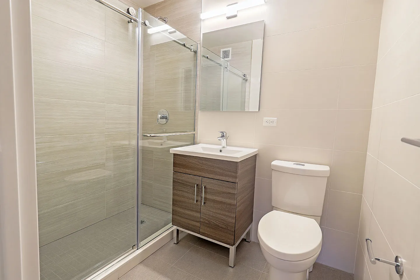 A bathroom featuring a toilet, sink, and a shower stall, designed for functional and efficient use of space.