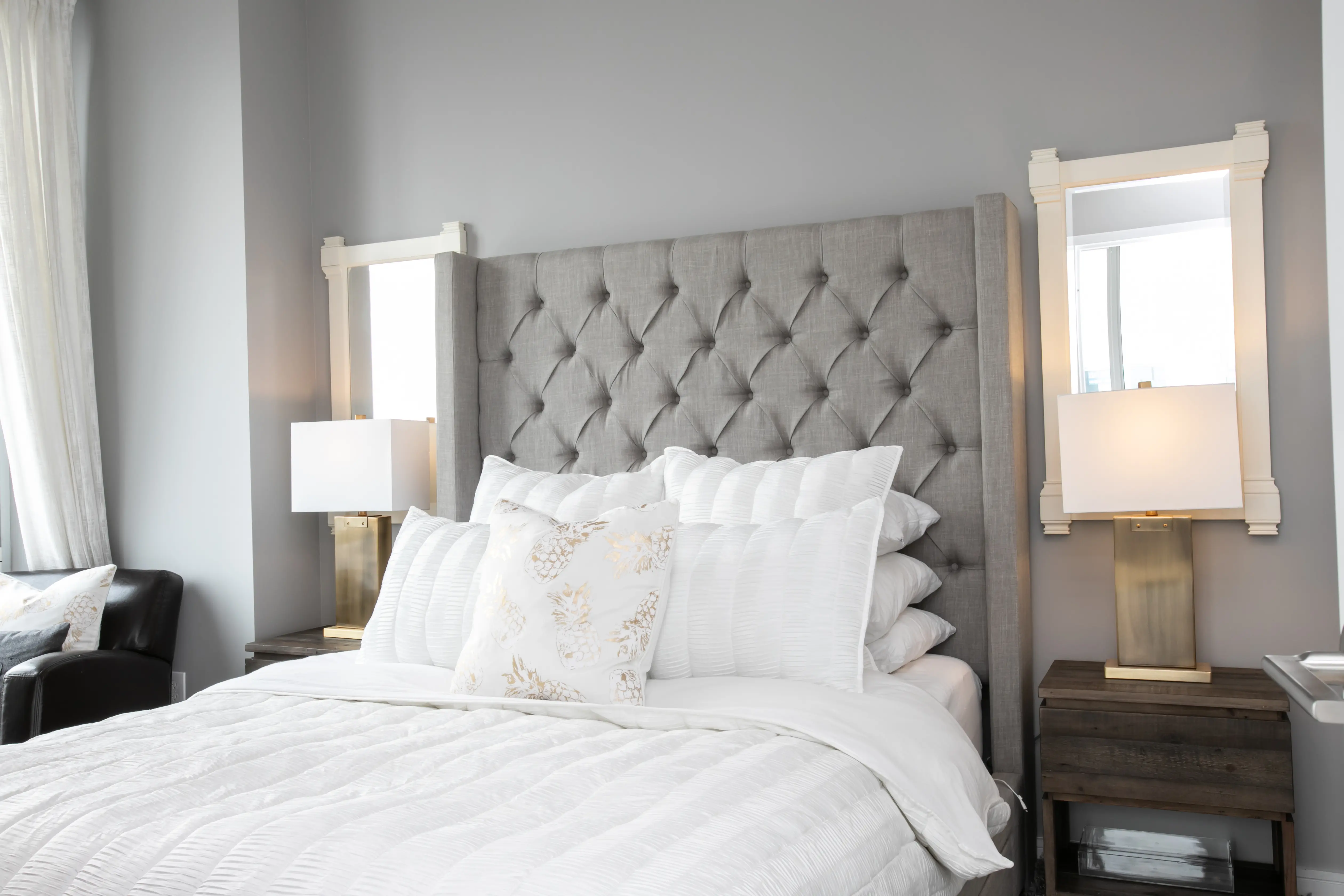 A cozy bed with a modern gray headboard, elegantly arranged with pillows and bedding.
