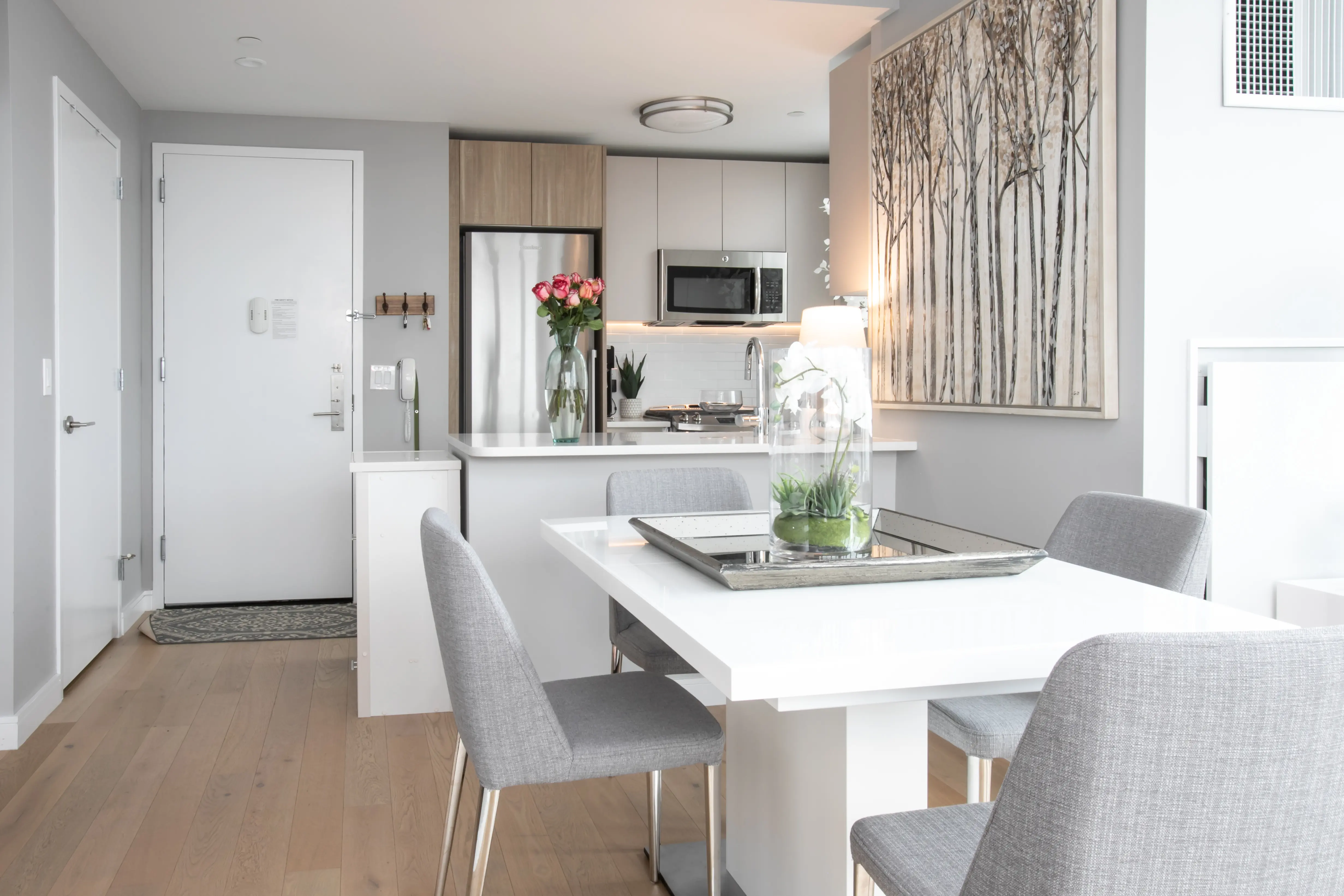 A modern kitchen and dining area featuring sleek white walls and contemporary furnishings.