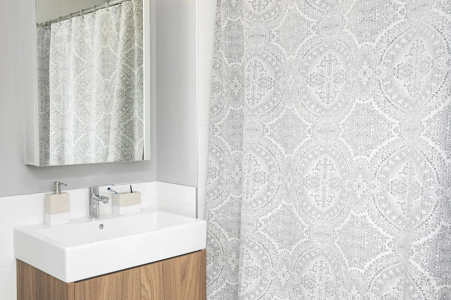 A clean bathroom showcasing a shower curtain and a sink, with soft lighting and minimal decor.