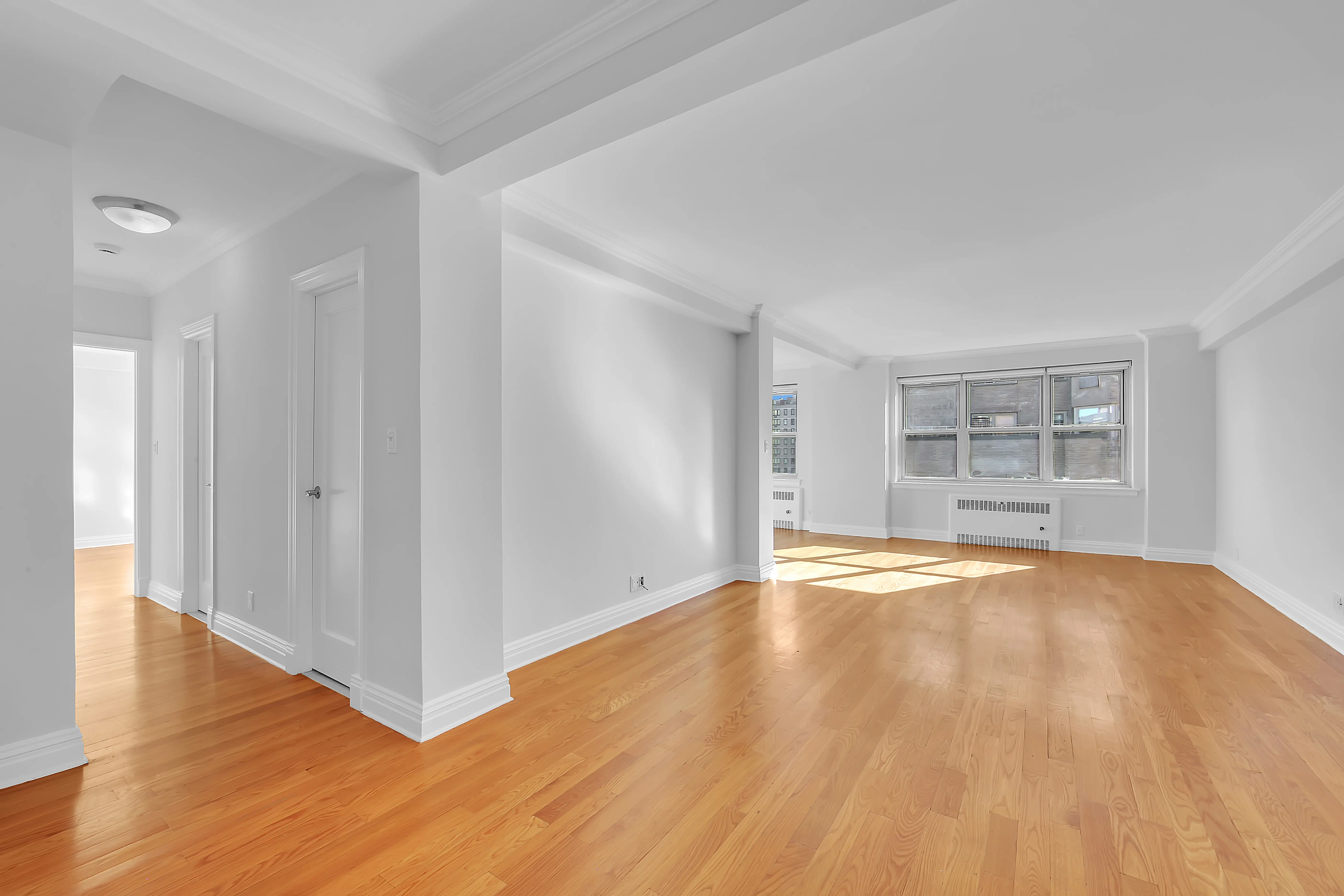 An empty room featuring hardwood floors and white walls, creating a bright and spacious atmosphere.