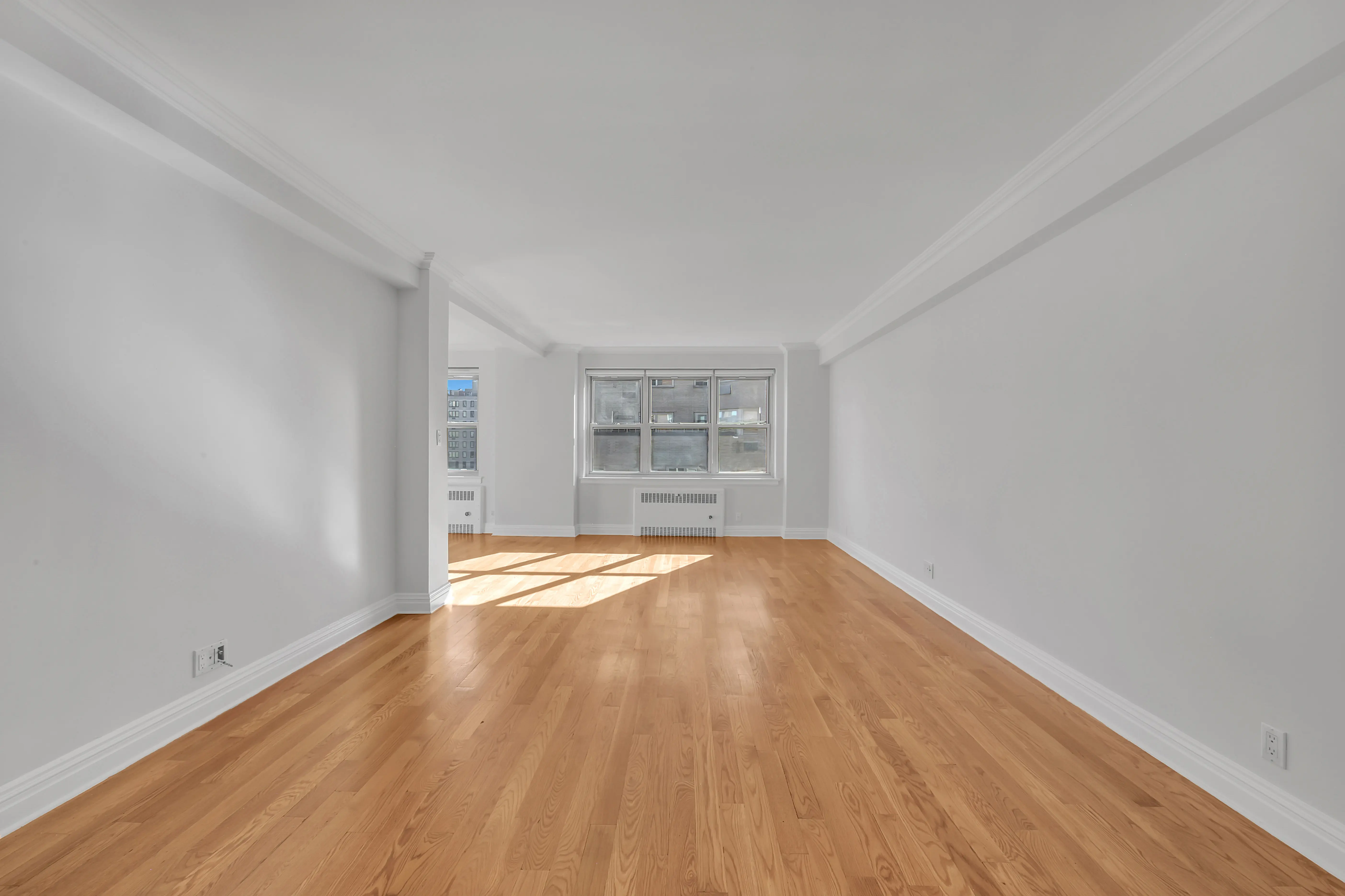 An empty room featuring hardwood floors and white walls, creating a bright and spacious atmosphere.