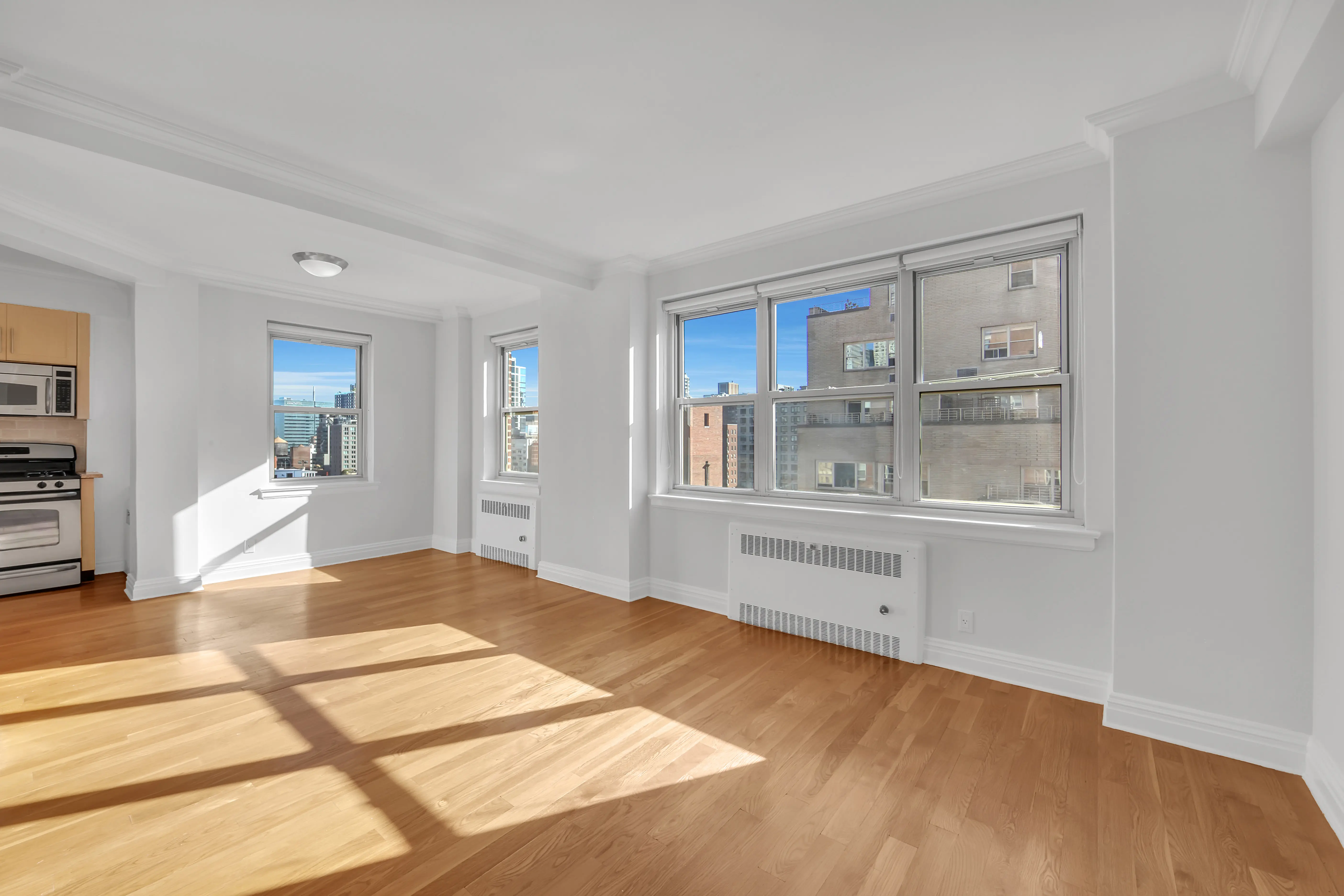 An empty room featuring hardwood floors and large windows allowing natural light to enter.