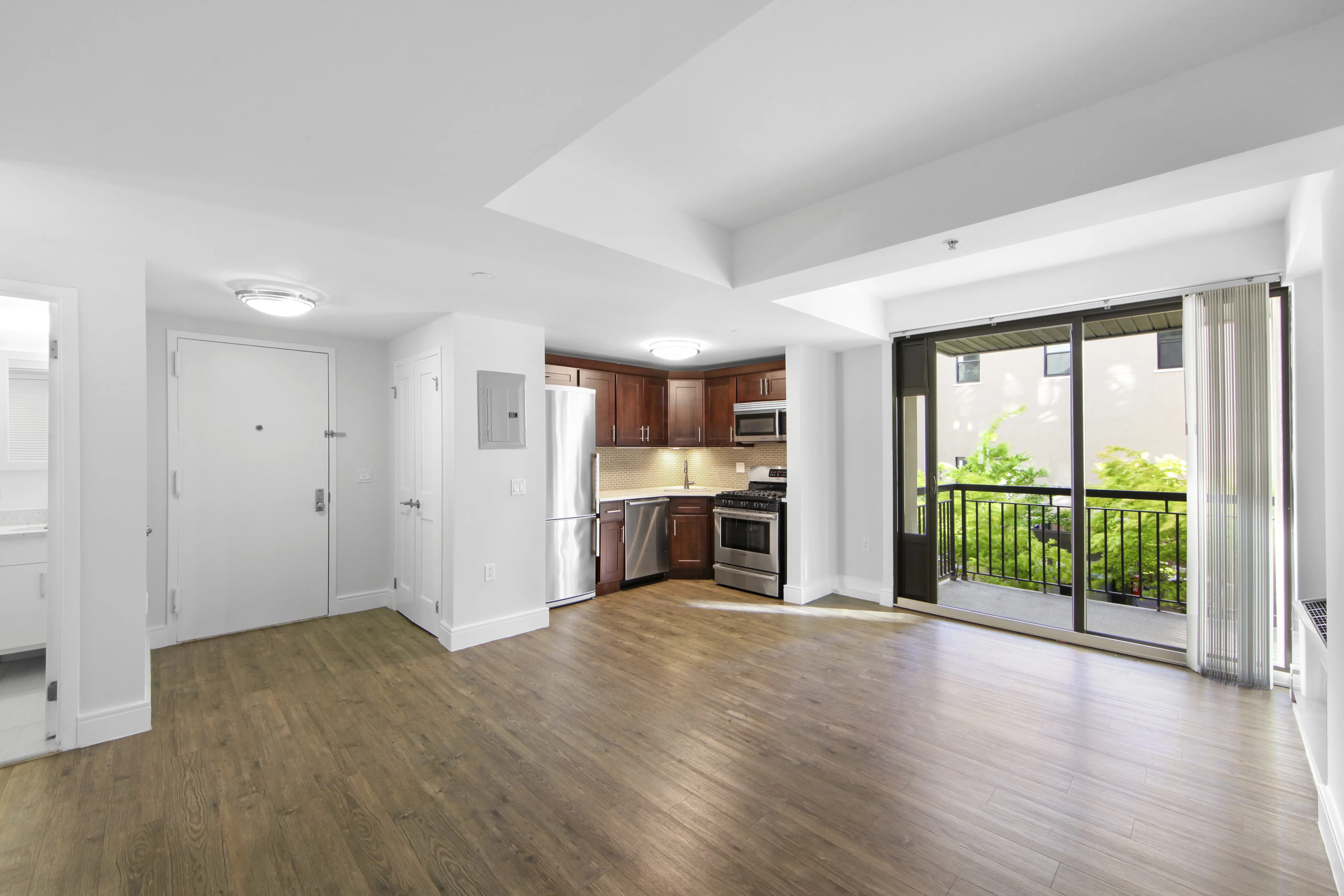 A spacious living room featuring hardwood floors and a sliding glass door leading to an outdoor area.