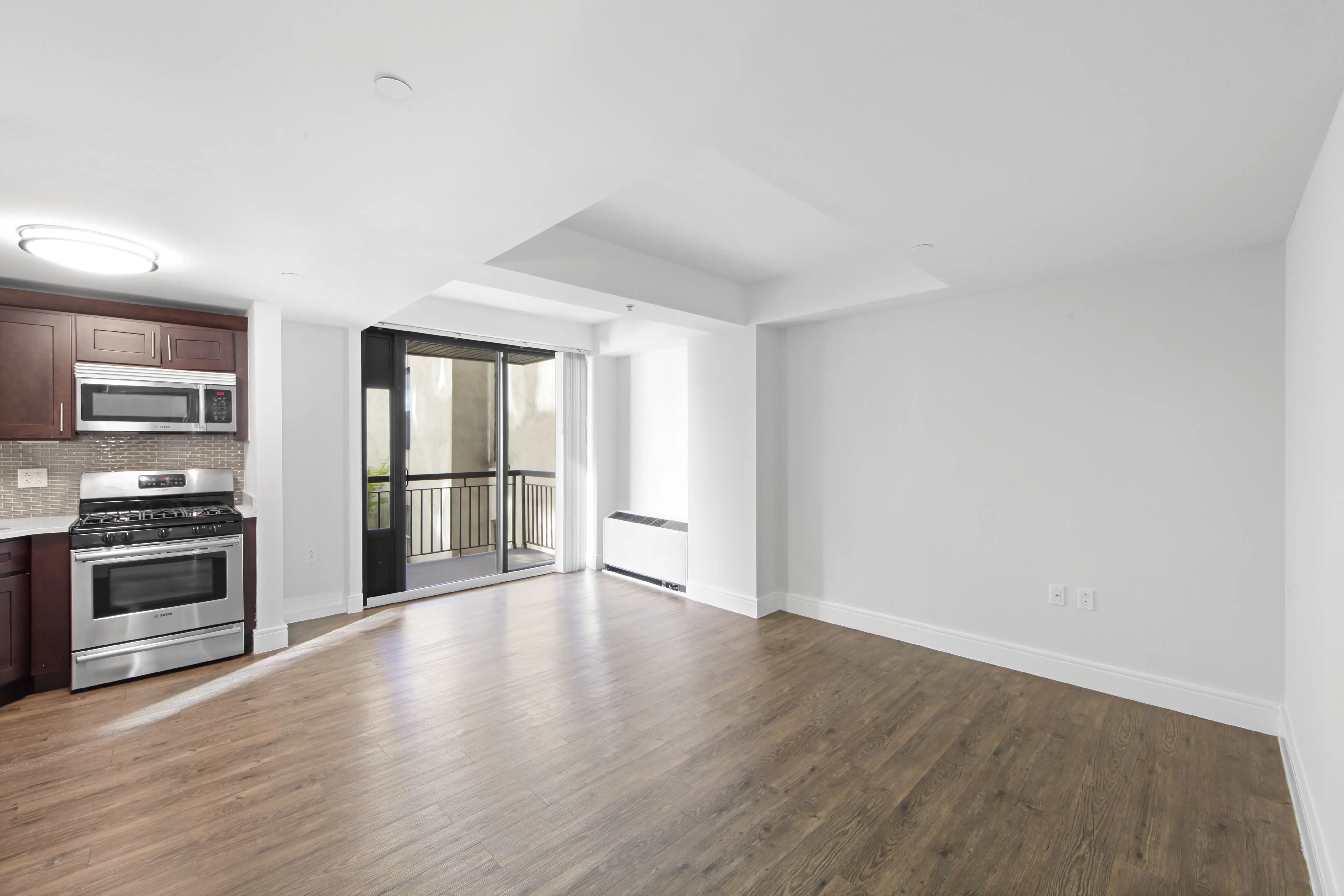 An empty kitchen featuring hardwood floors and modern stainless steel appliances.