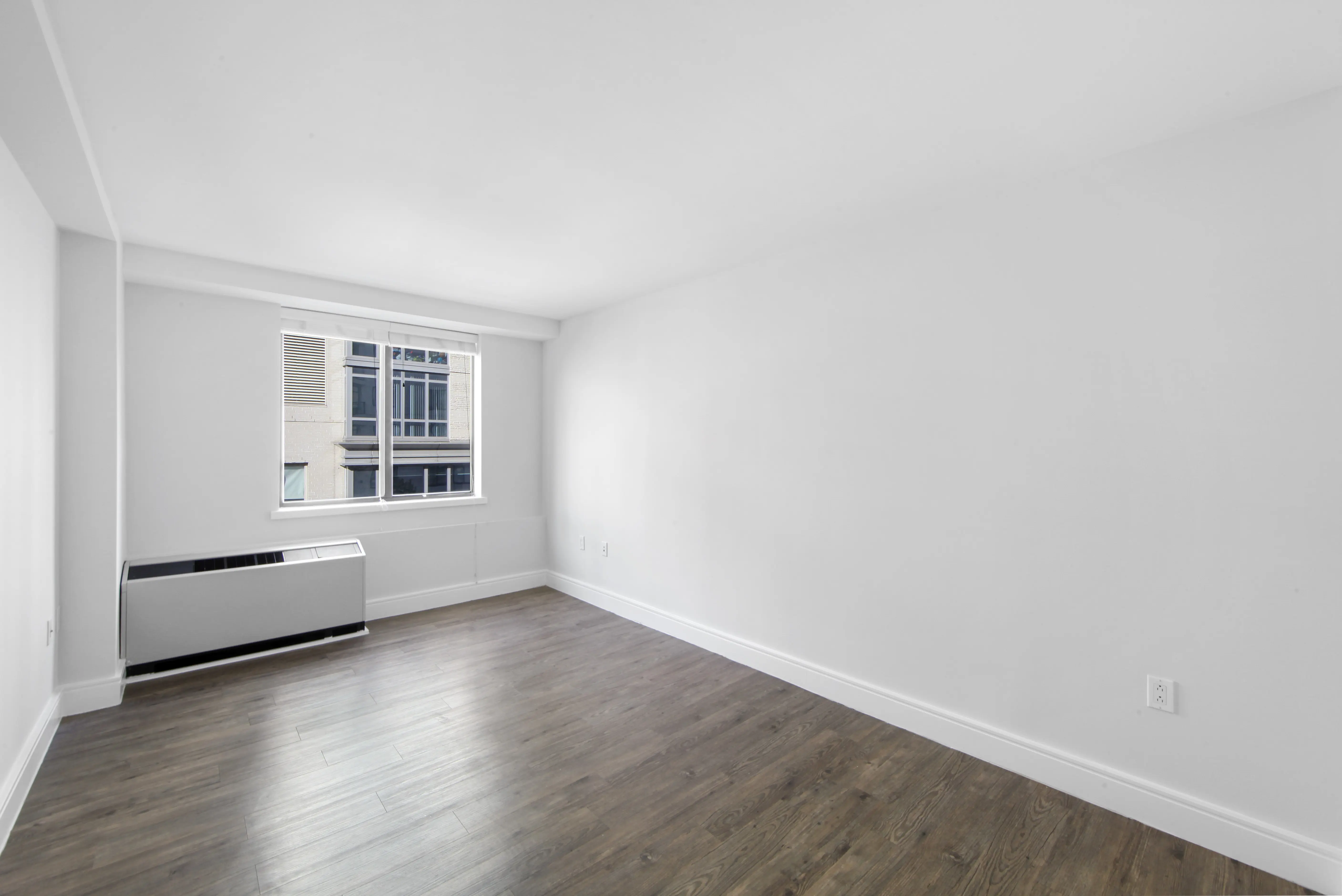 A vacant room with polished hardwood floors and clean white walls, offering a minimalist and open feel.