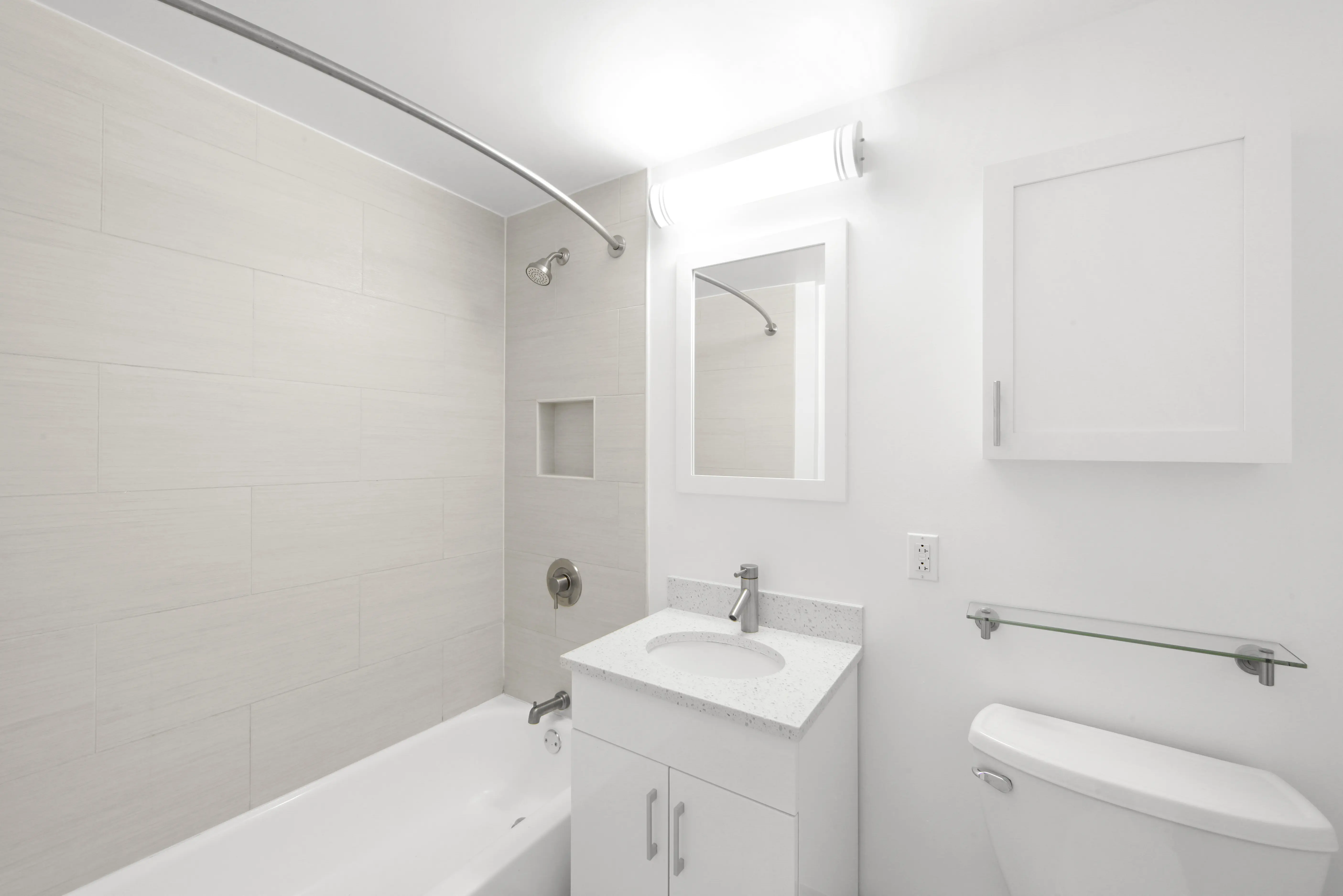 A clean white bathroom featuring a toilet, sink, and shower, showcasing a modern and minimalist design.
