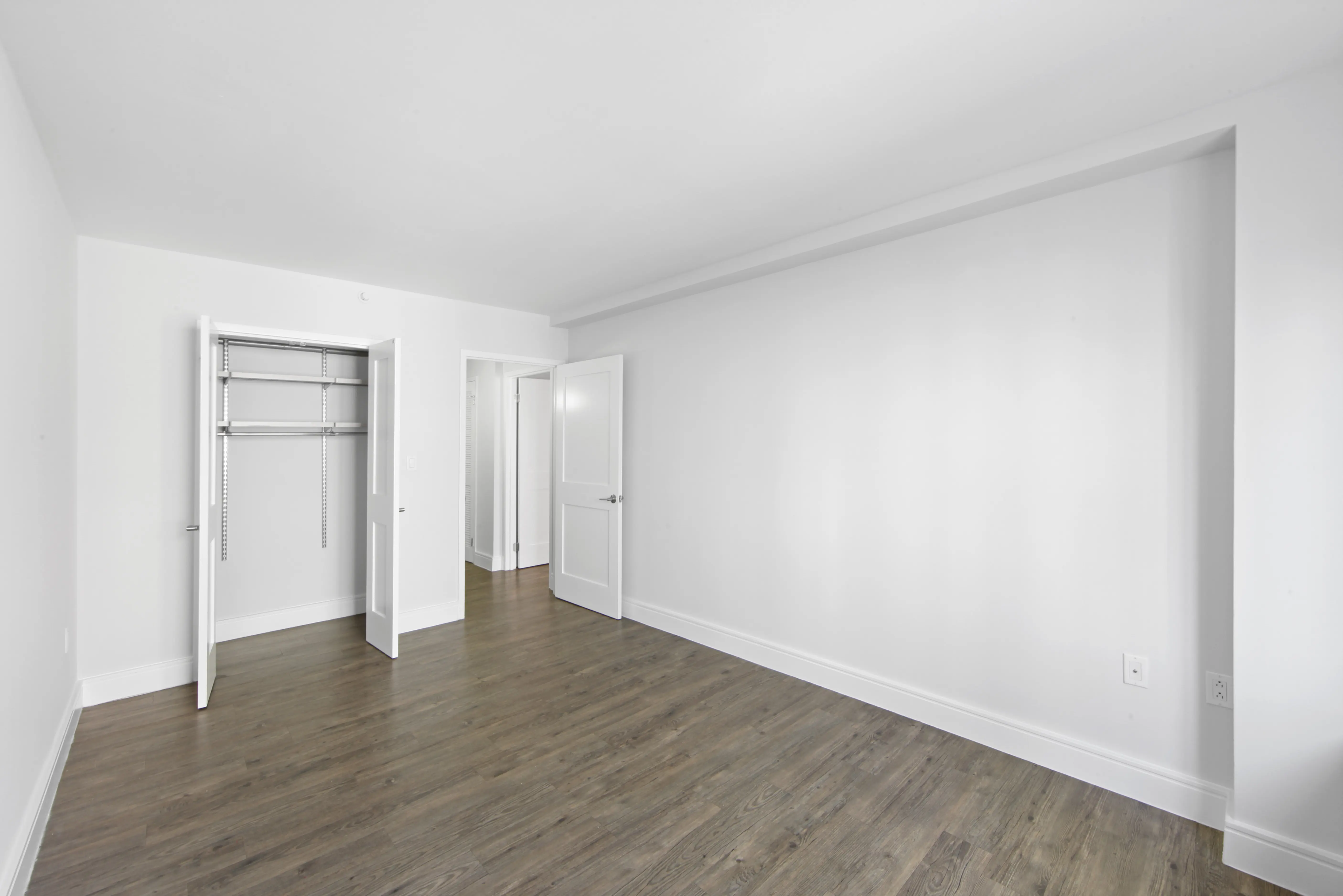An empty room featuring white walls and polished wooden floors, creating a bright and spacious atmosphere.