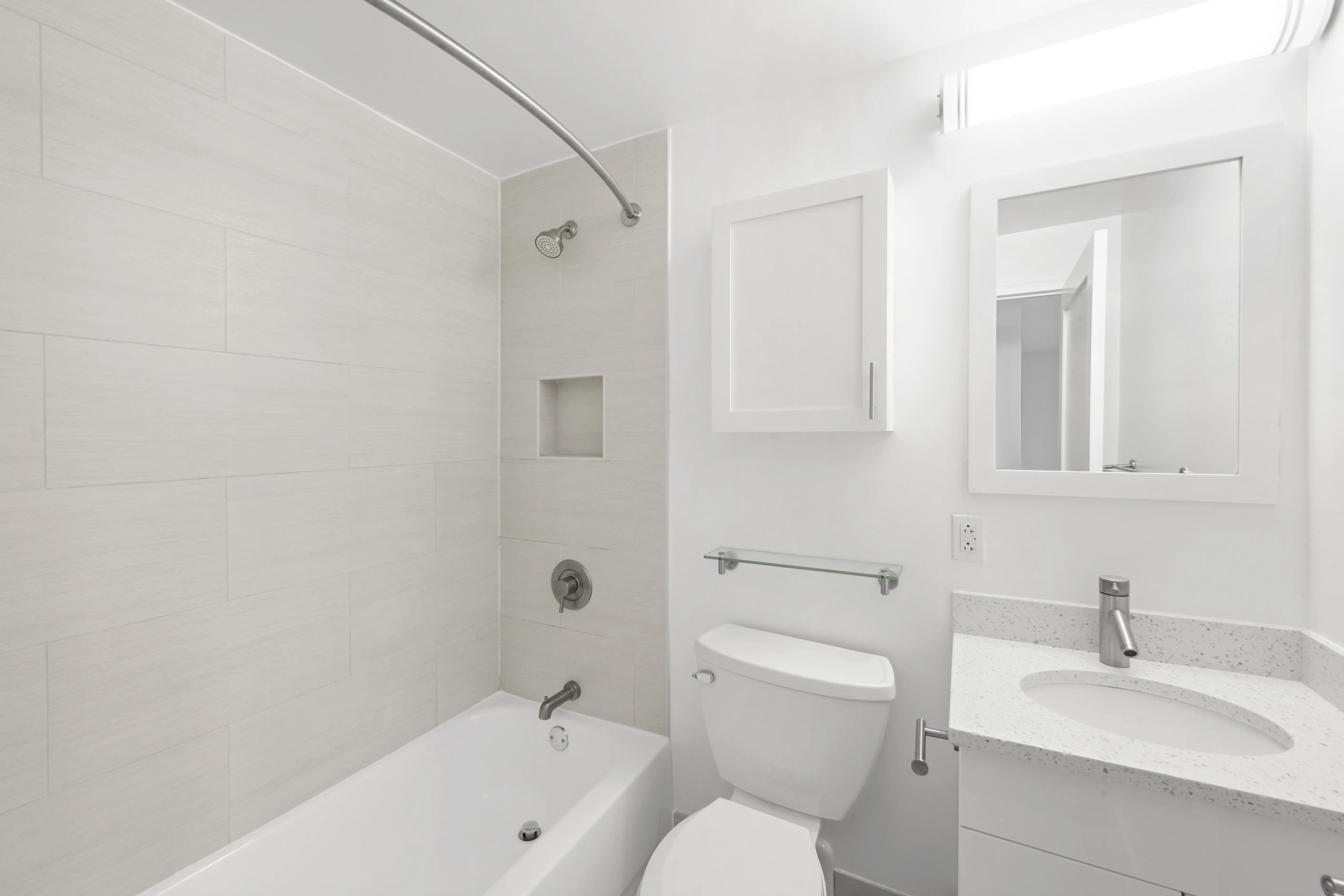A clean white bathroom featuring a toilet, sink, and shower, showcasing a modern and minimalist design.
