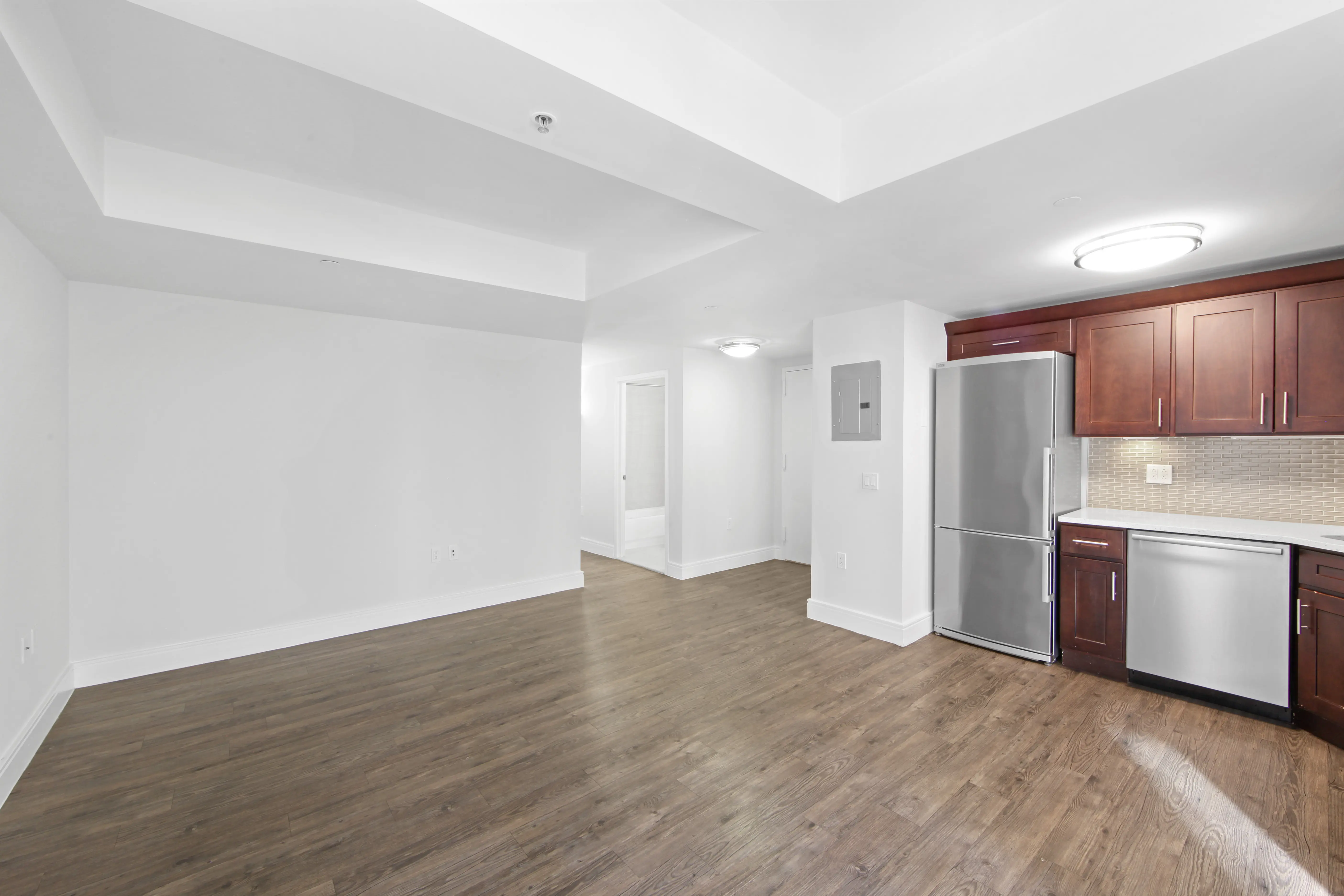 An empty kitchen featuring hardwood floors and white walls, creating a bright and spacious atmosphere.