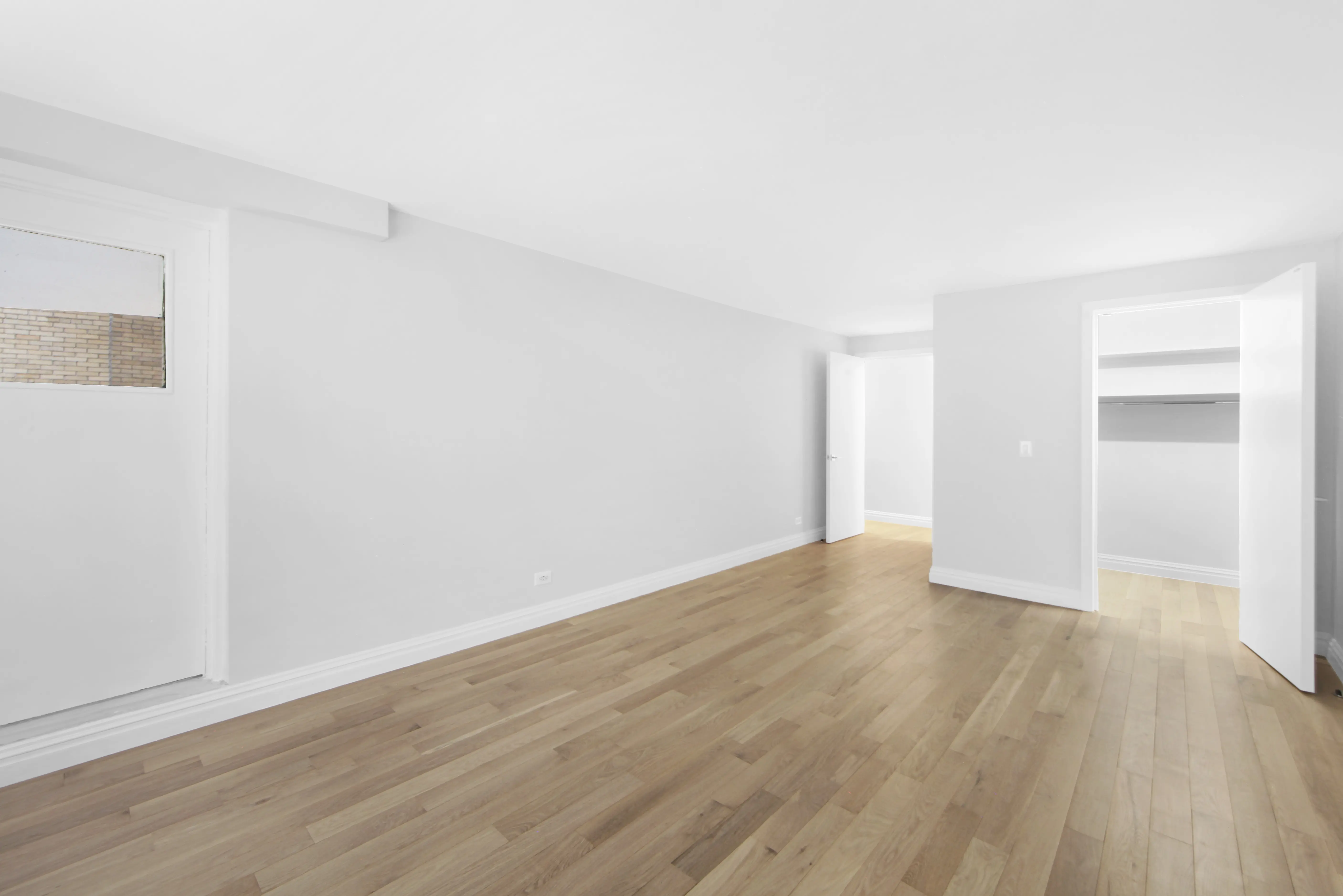 A vacant room with polished hardwood floors and clean white walls, offering a minimalist and open feel.