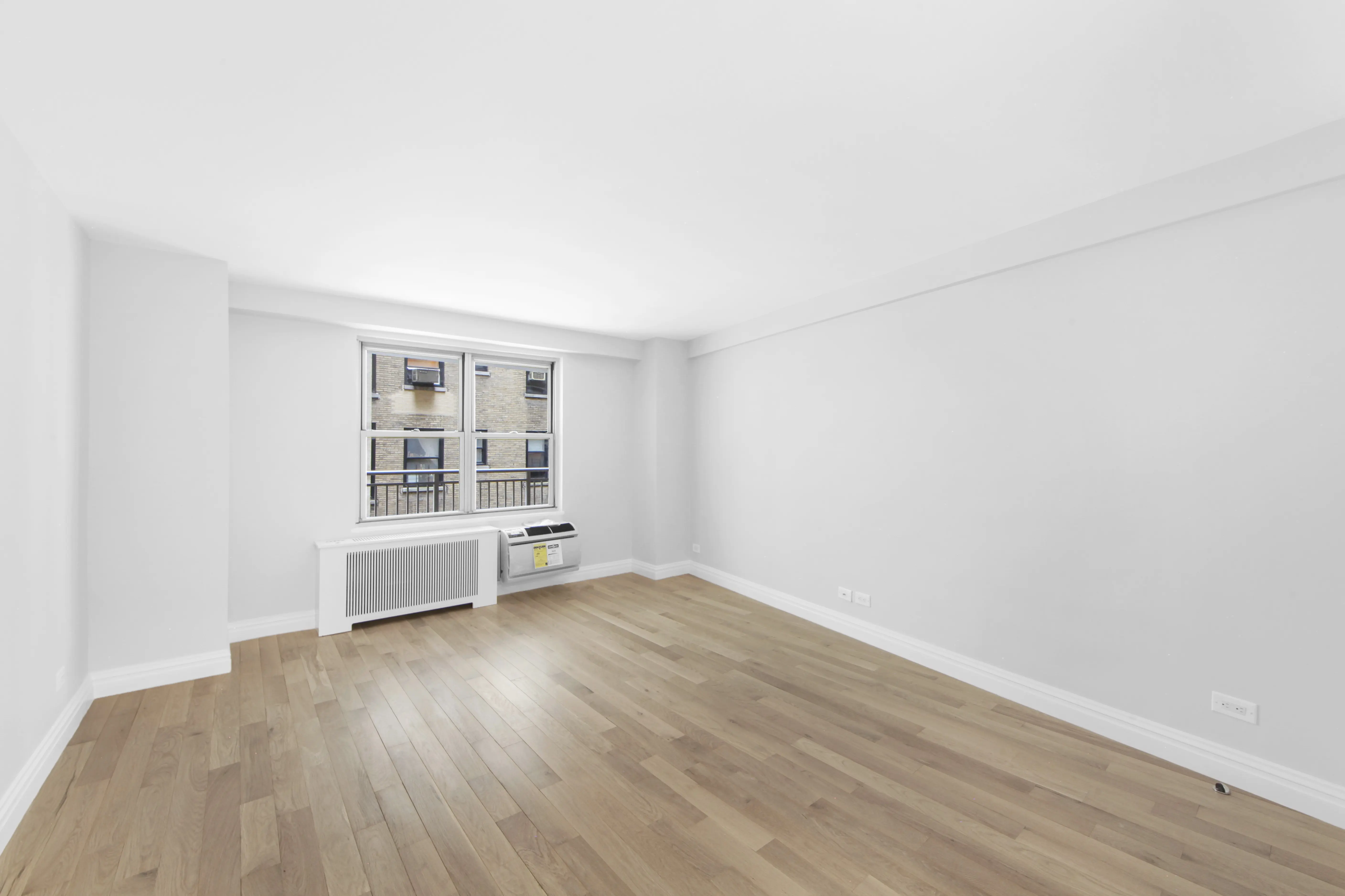 An empty room featuring hardwood floors and white walls, creating a bright and spacious atmosphere.