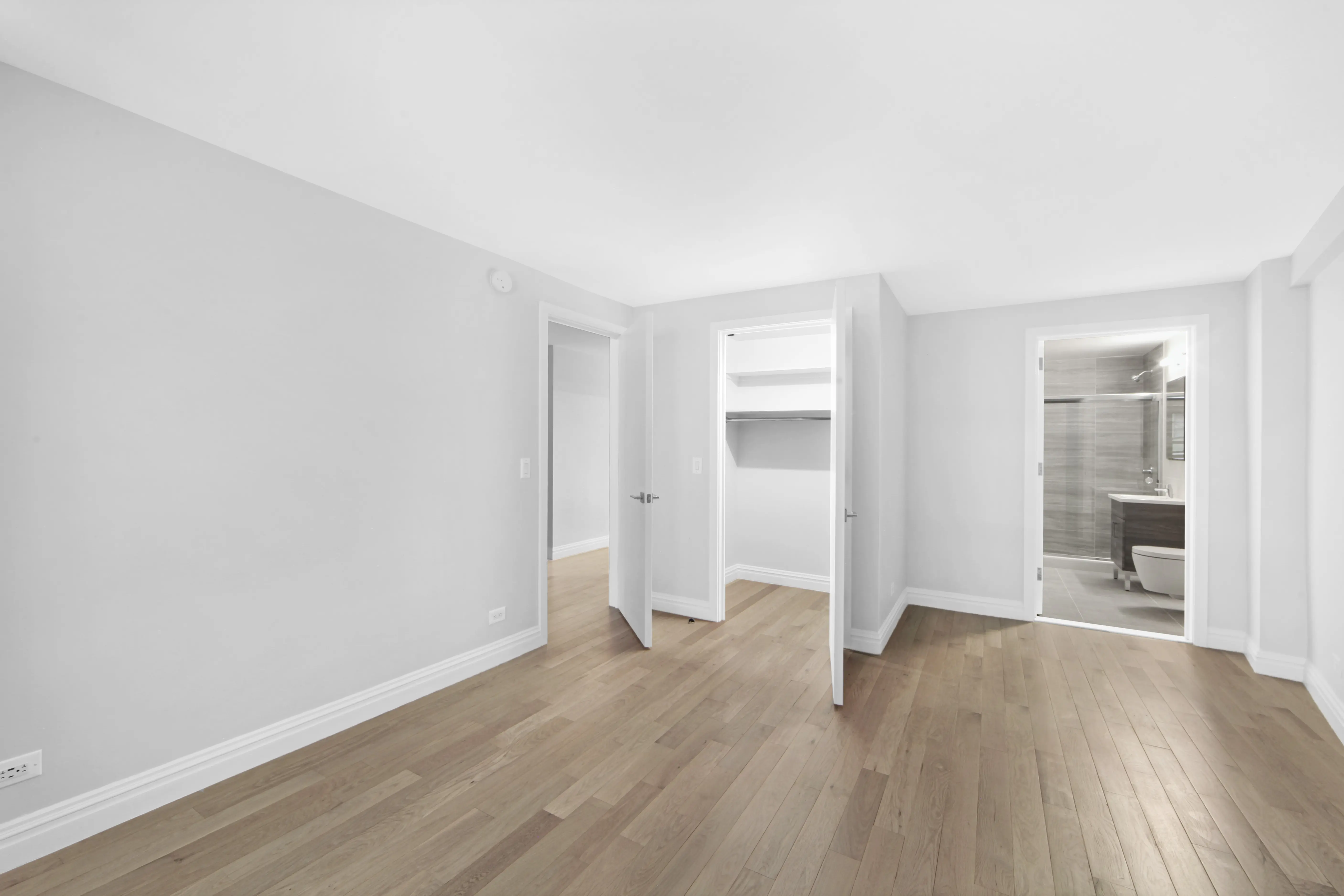 An empty room featuring white walls and polished hardwood floors, creating a bright and spacious atmosphere.