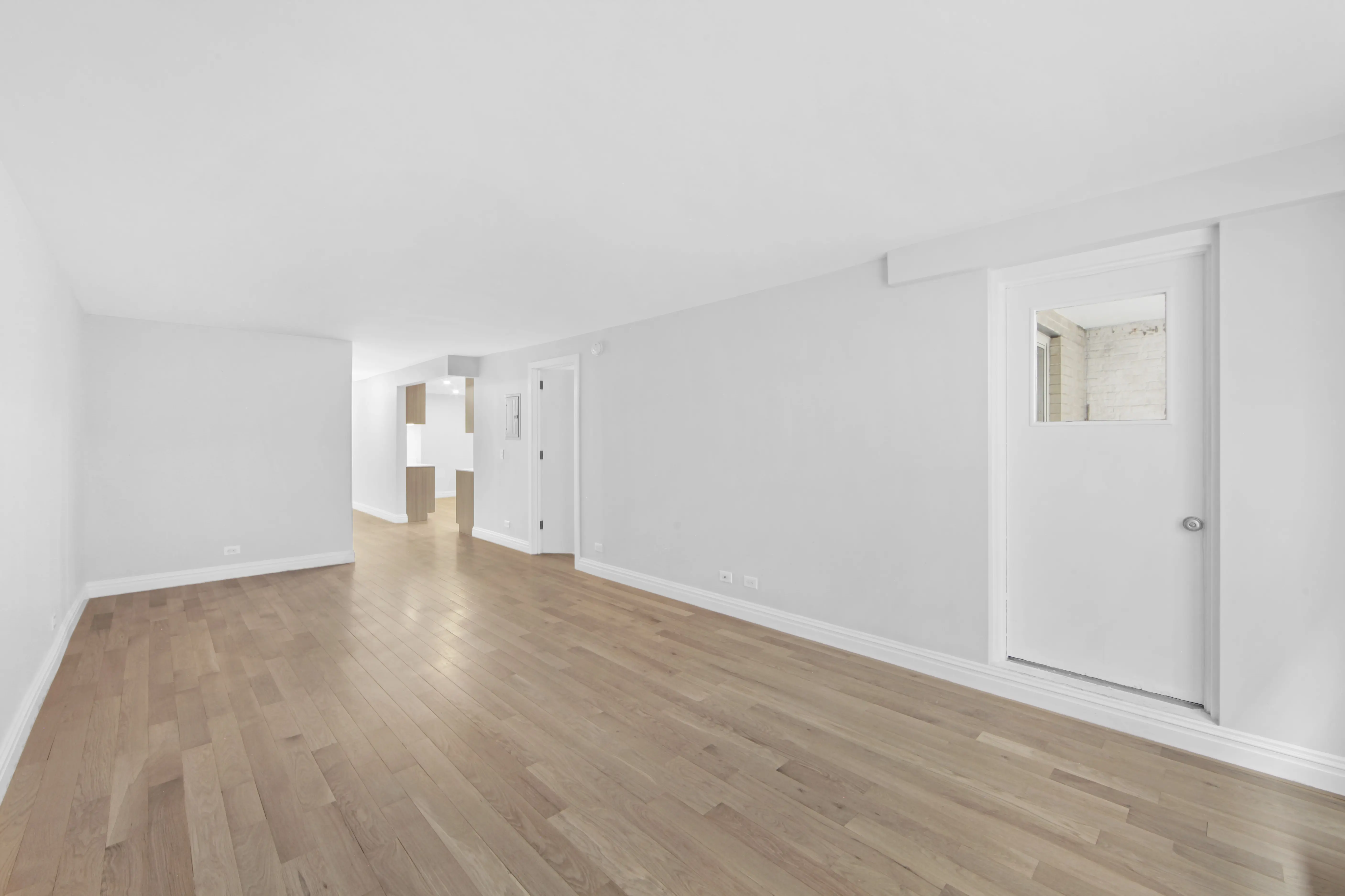 An empty room featuring hardwood floors and white walls, creating a bright and spacious atmosphere.