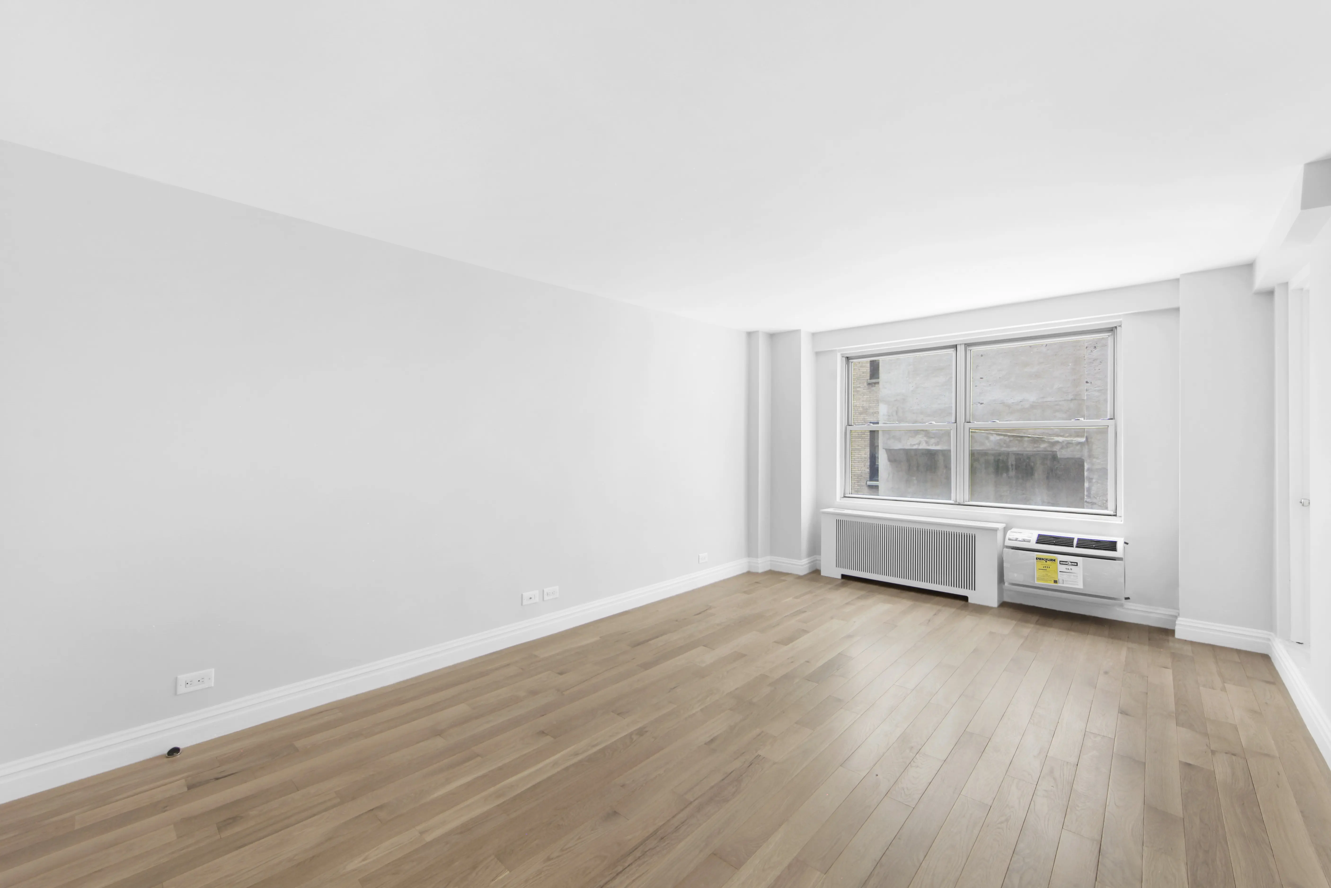 A vacant room with polished hardwood floors and clean white walls, offering a minimalist and open feel.