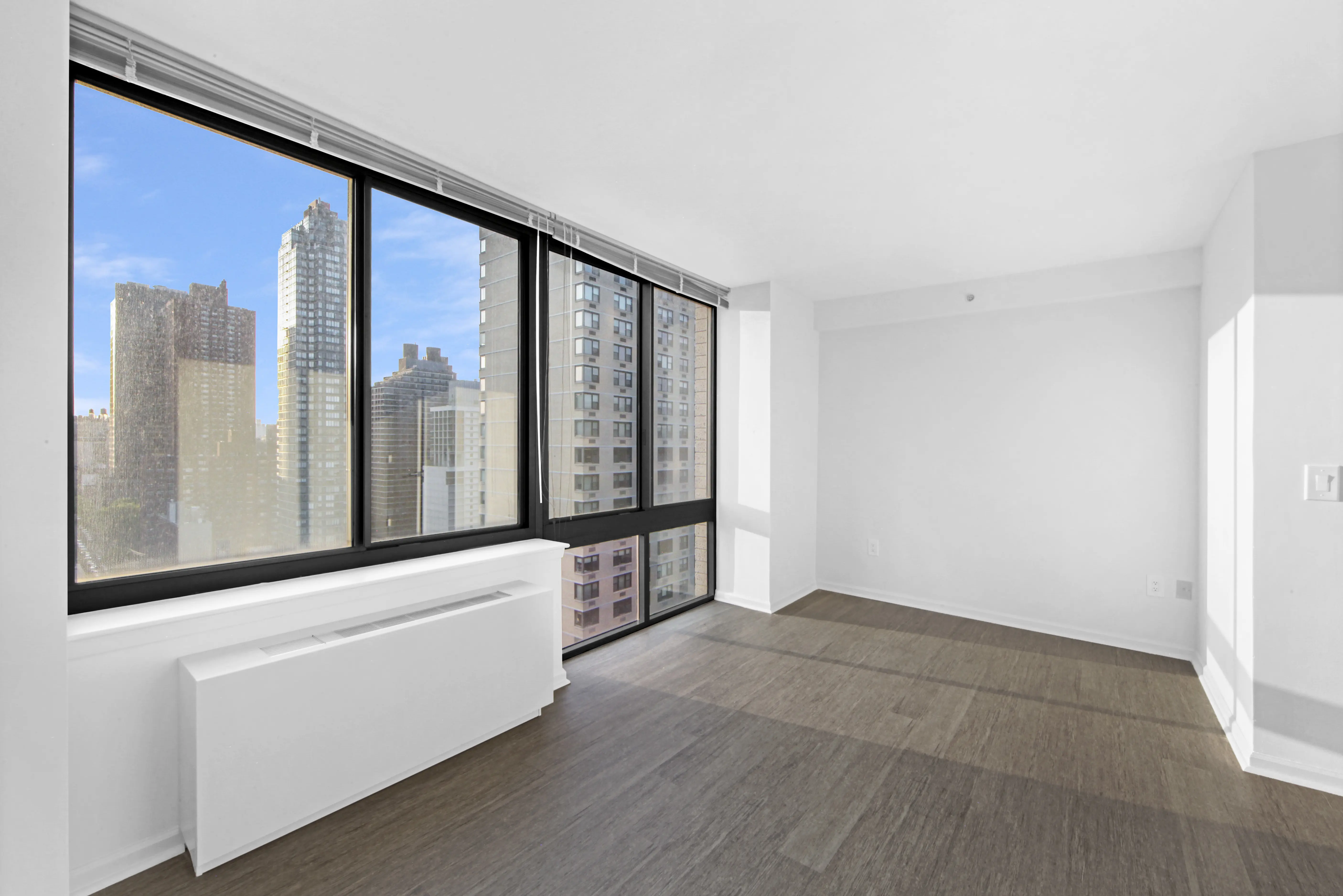 An empty room featuring hardwood floors and a window allowing natural light to enter.