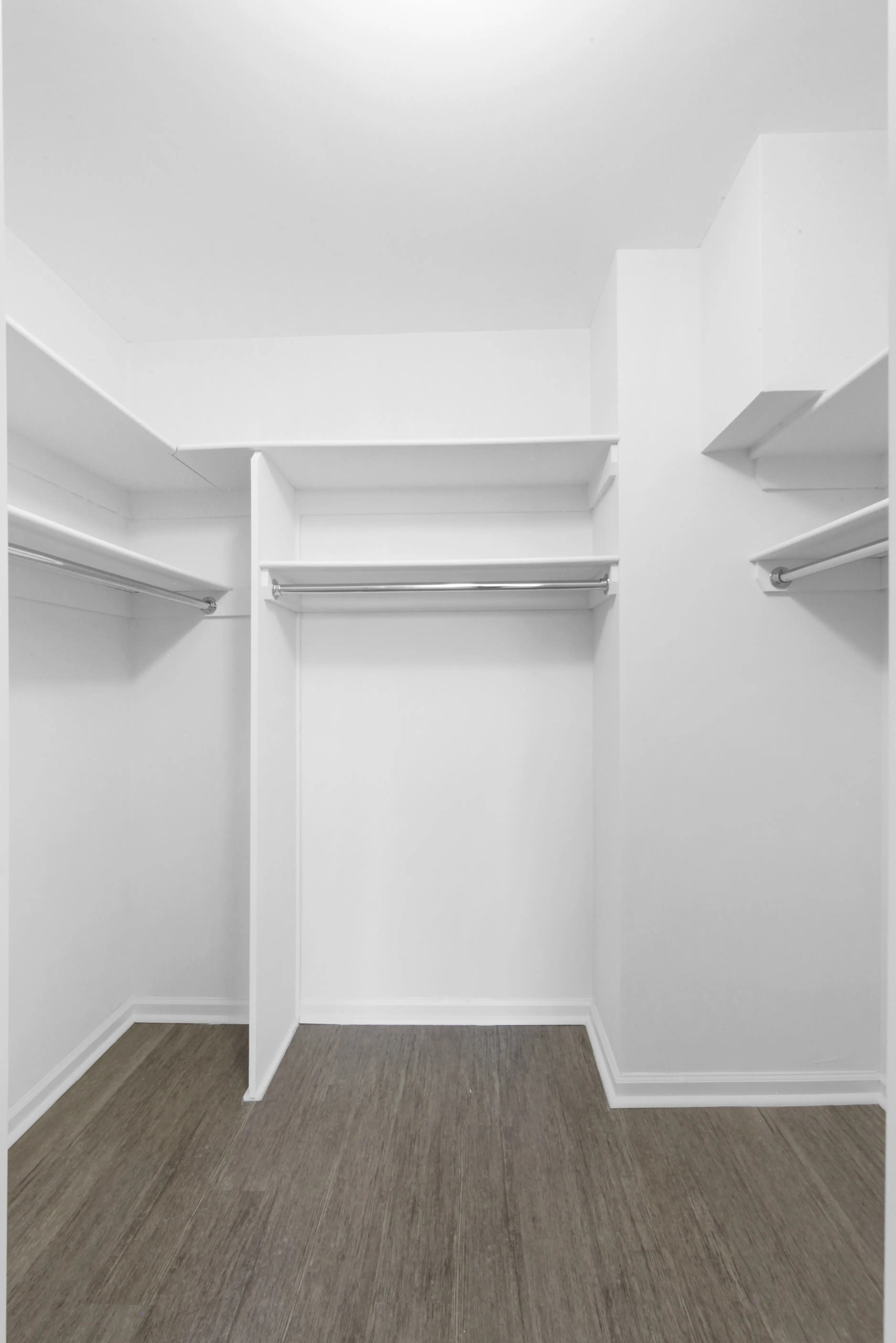 An empty closet featuring a wooden floor and white walls, creating a clean and spacious appearance.