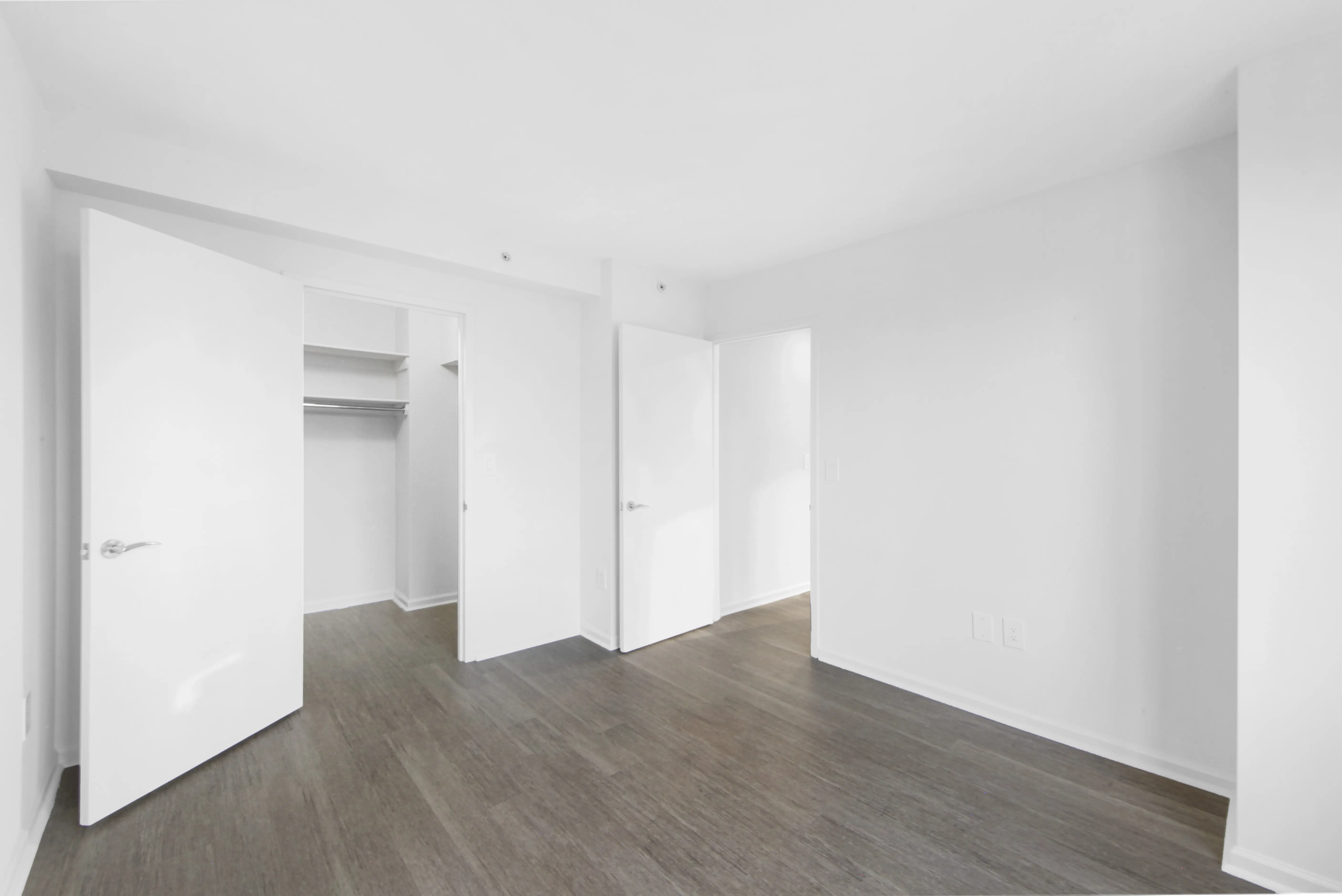 An empty room featuring white walls and polished wooden floors, creating a bright and spacious atmosphere.