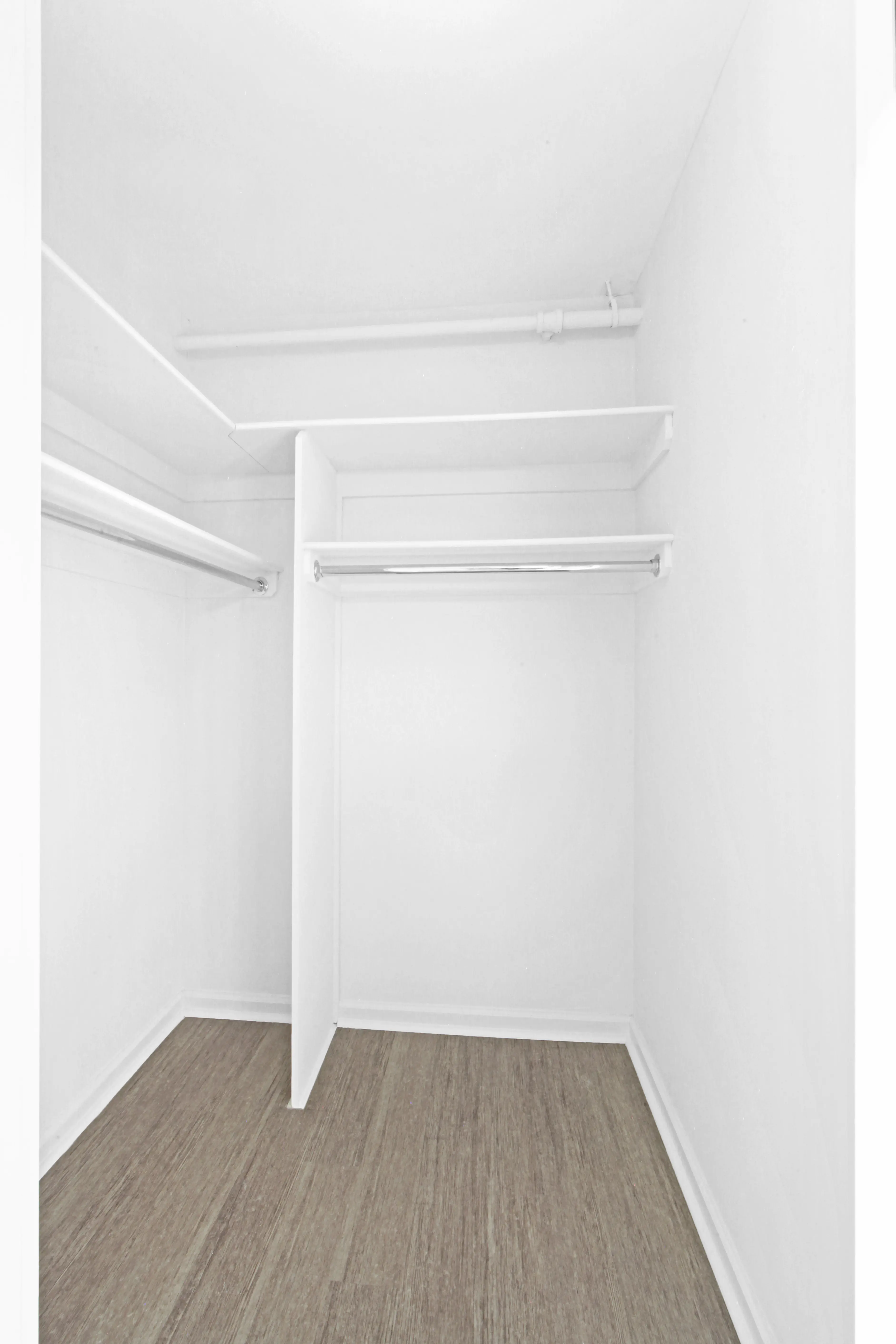 A bright white room featuring a closet and a warm wooden floor.