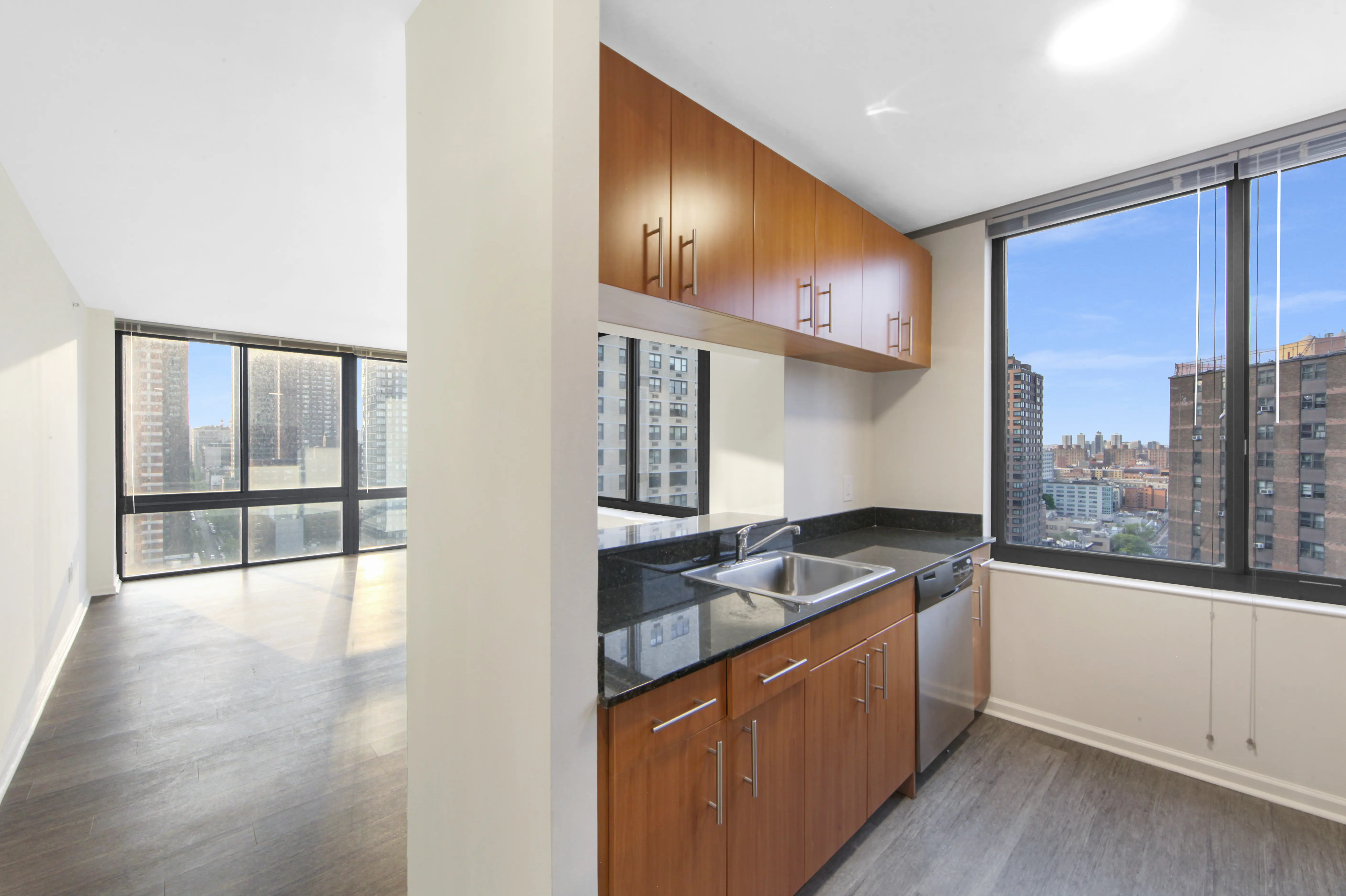 A spacious kitchen with a large window allowing natural light, complemented by stylish wooden cabinets.