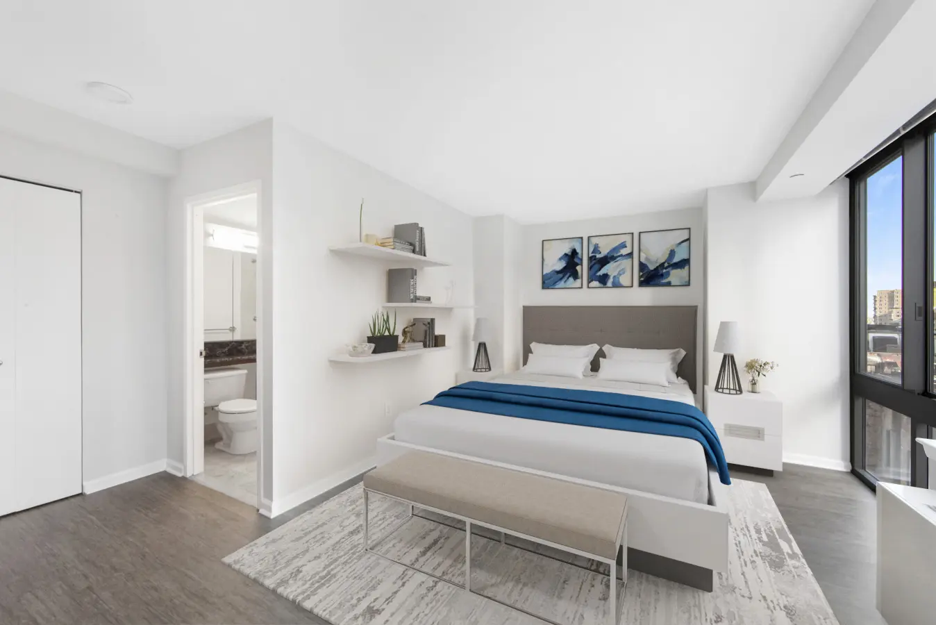 A cozy bedroom featuring a bed, a desk, and a window allowing natural light to enter the space.