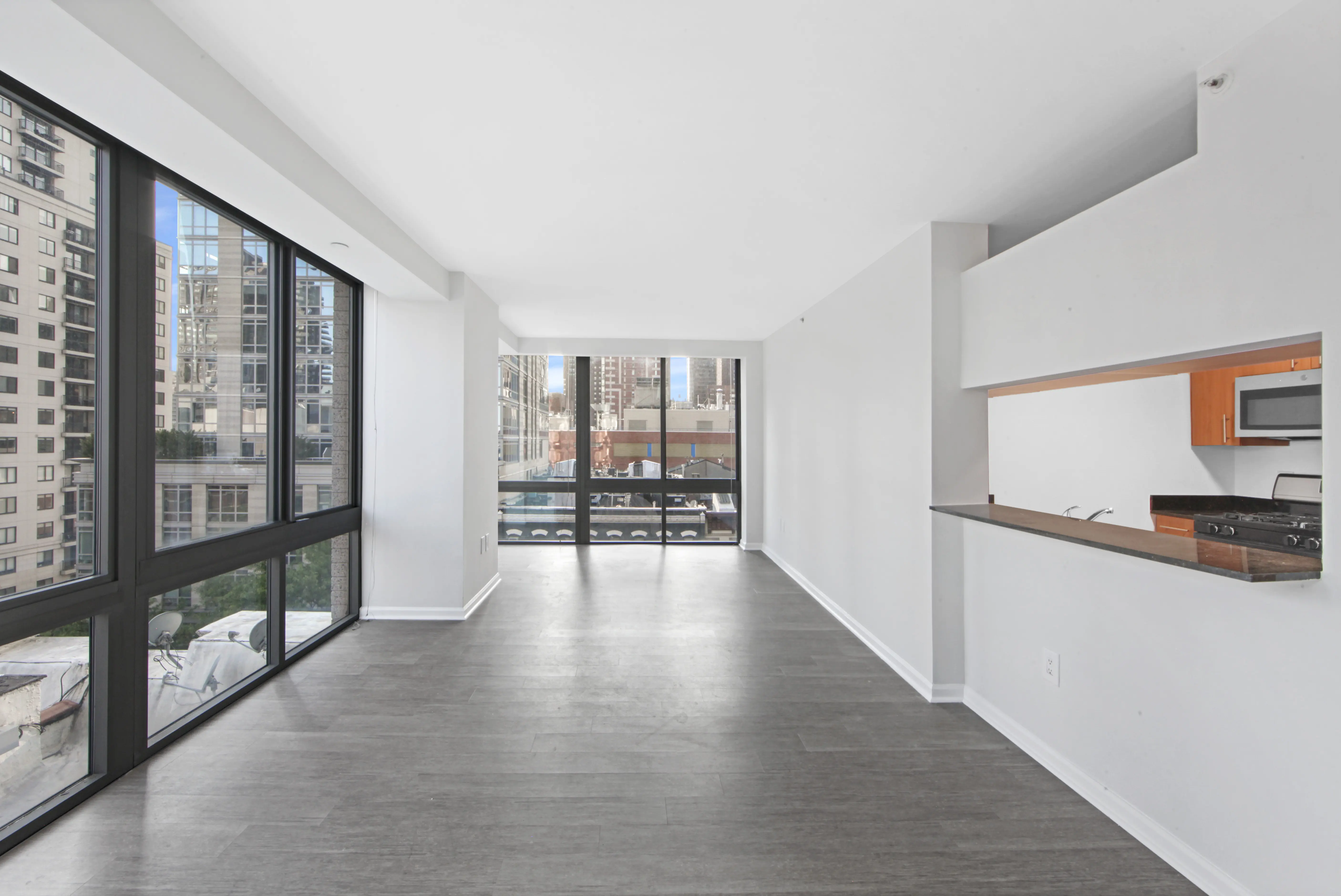 A long hallway featuring a kitchen and a panoramic view of the city skyline through large windows.