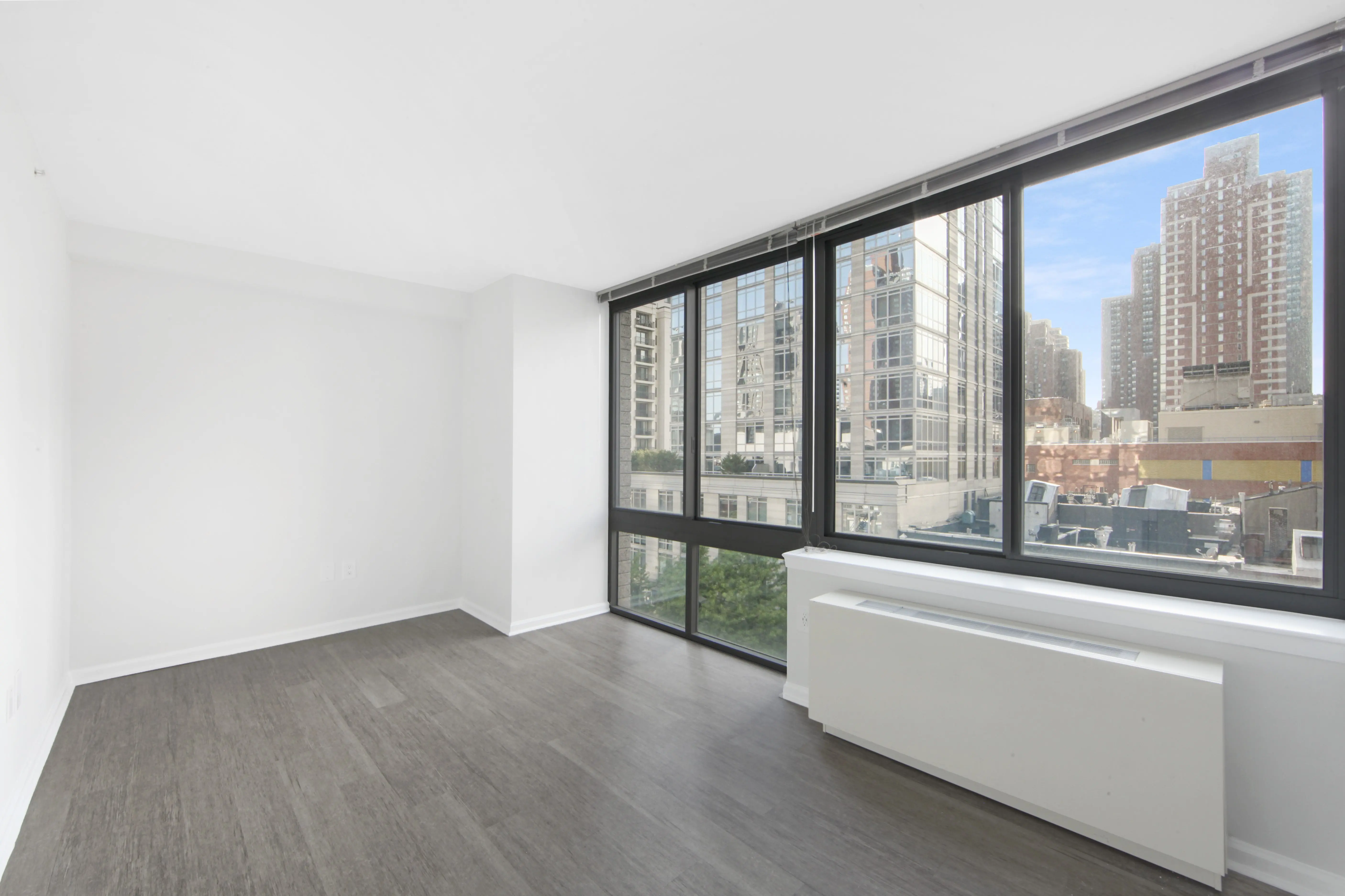 A vacant room with hardwood flooring and a window, creating a bright and open atmosphere.