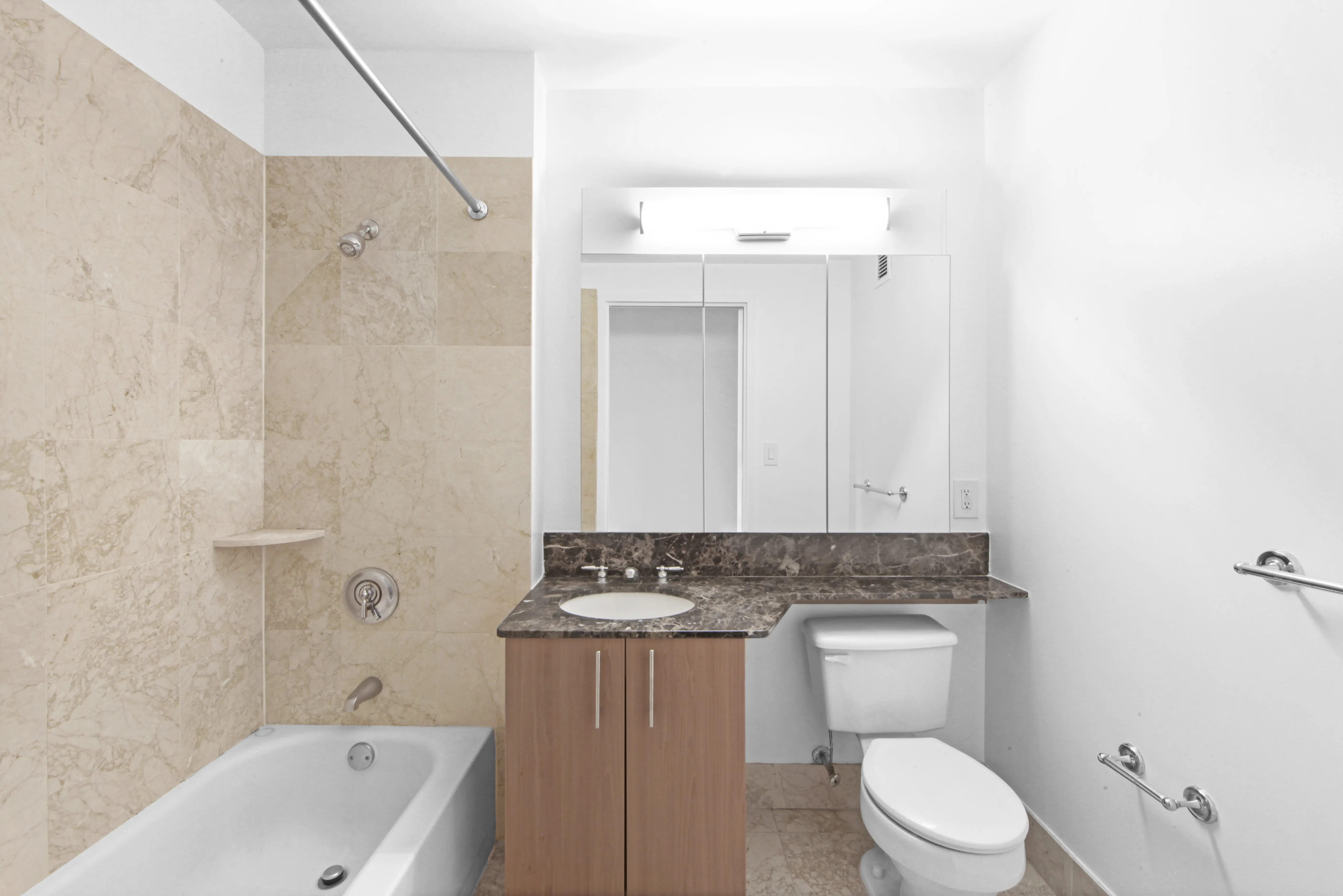 A modern bathroom containing a toilet, sink, and bathtub, emphasizing a tidy and organized space.