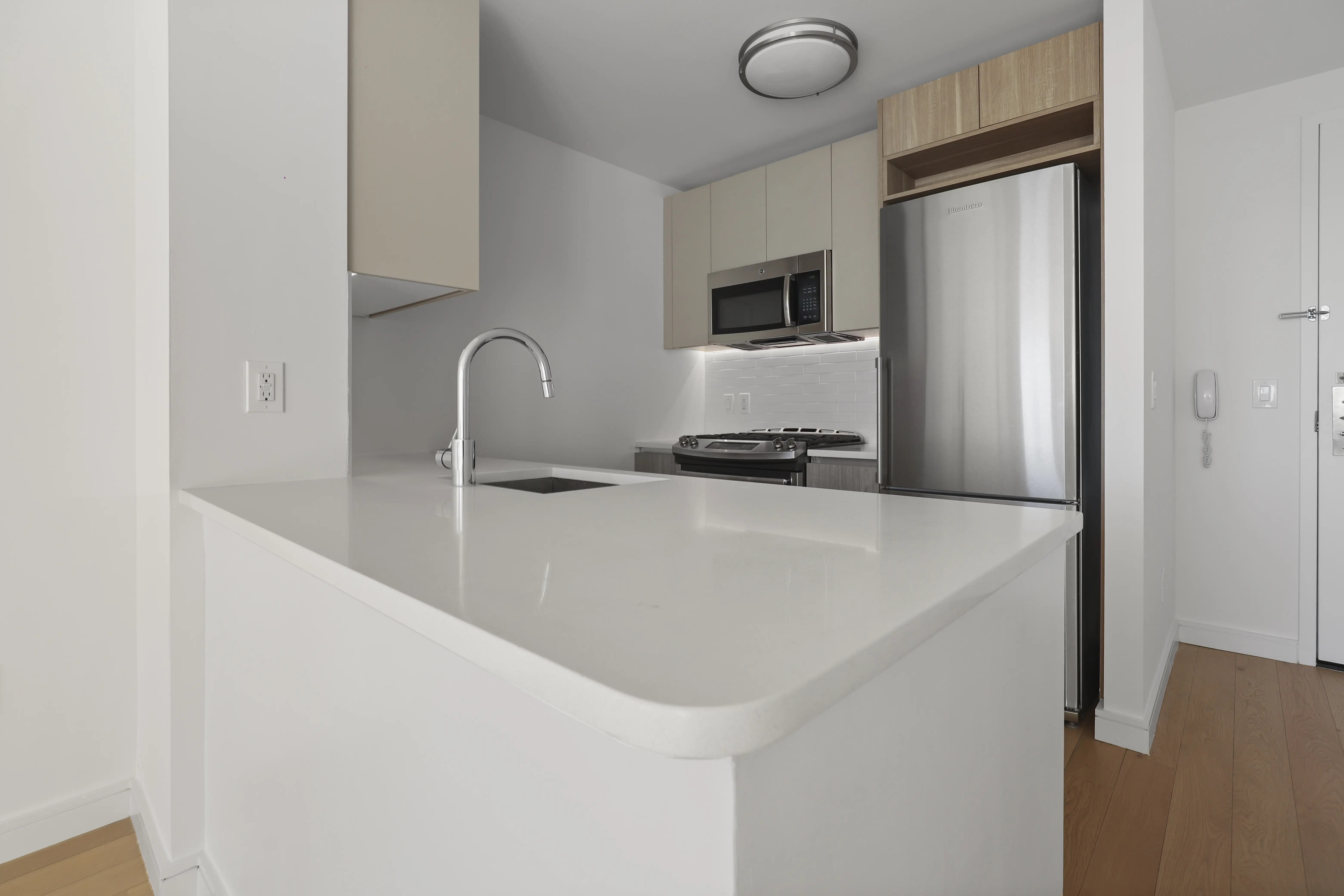 A modern kitchen featuring white countertops and sleek stainless steel appliances.