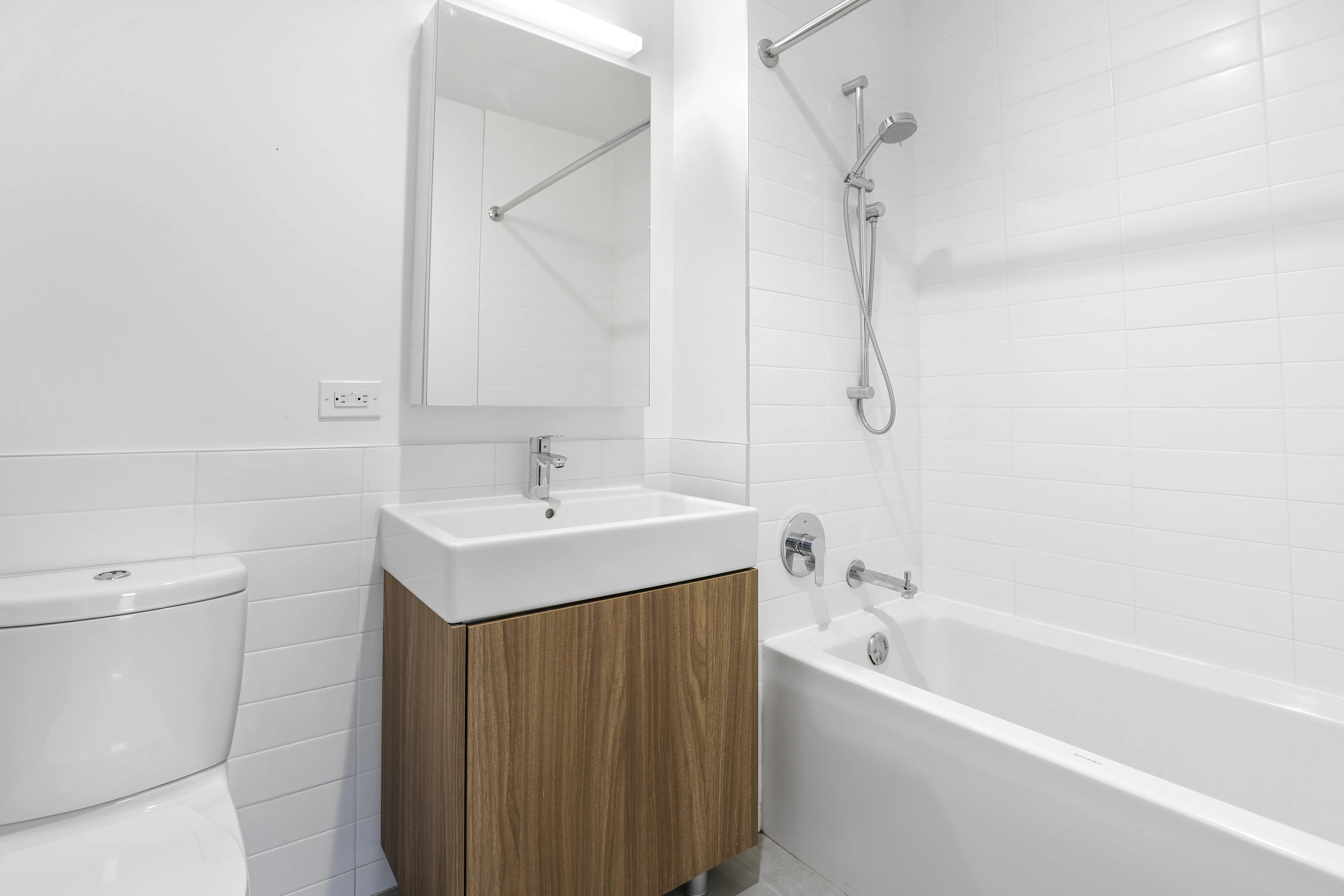 A clean bathroom featuring a white bathtub, toilet, and sink against a neutral backdrop.