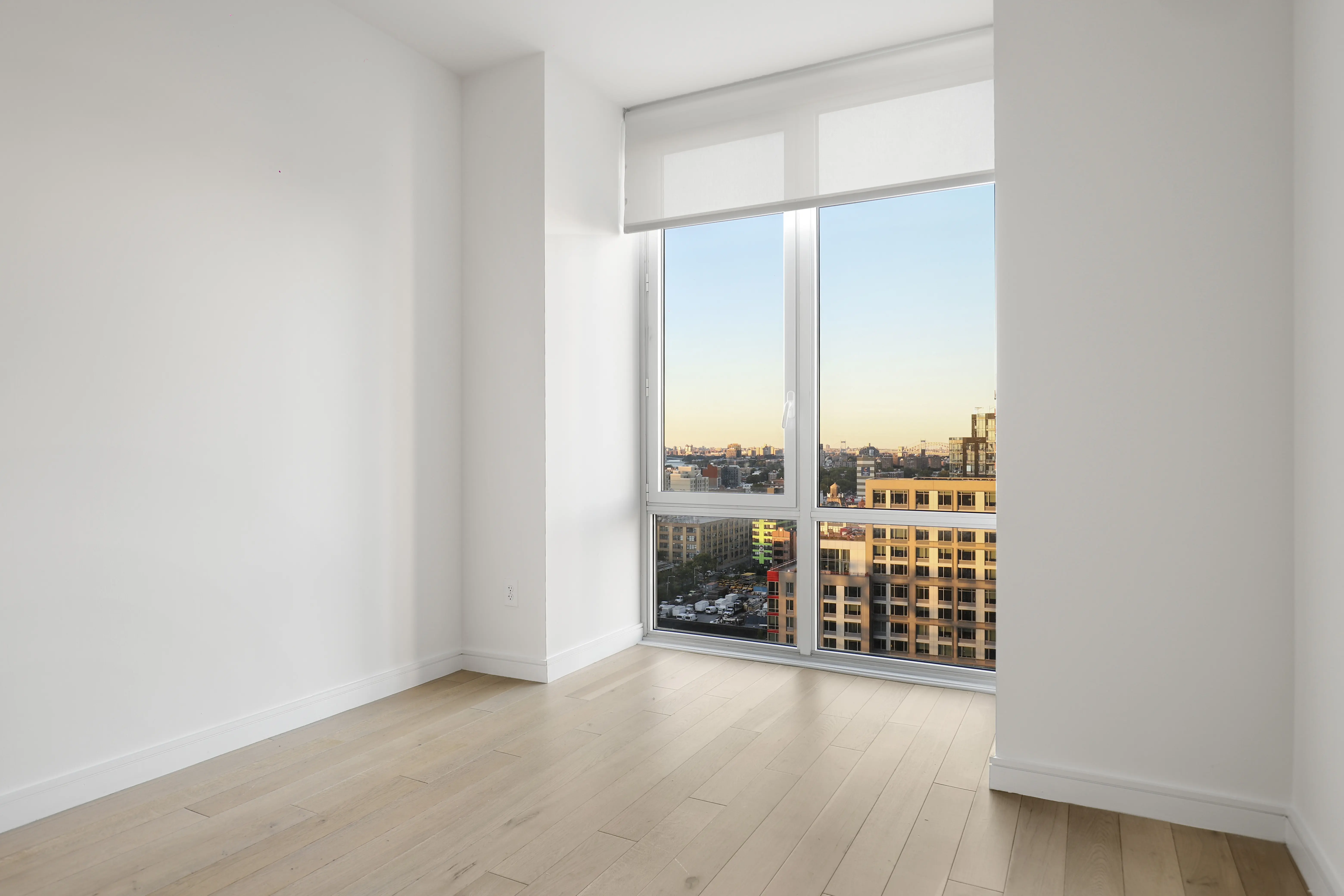 Empty room featuring large windows and polished hardwood floors, creating a bright and spacious atmosphere.
