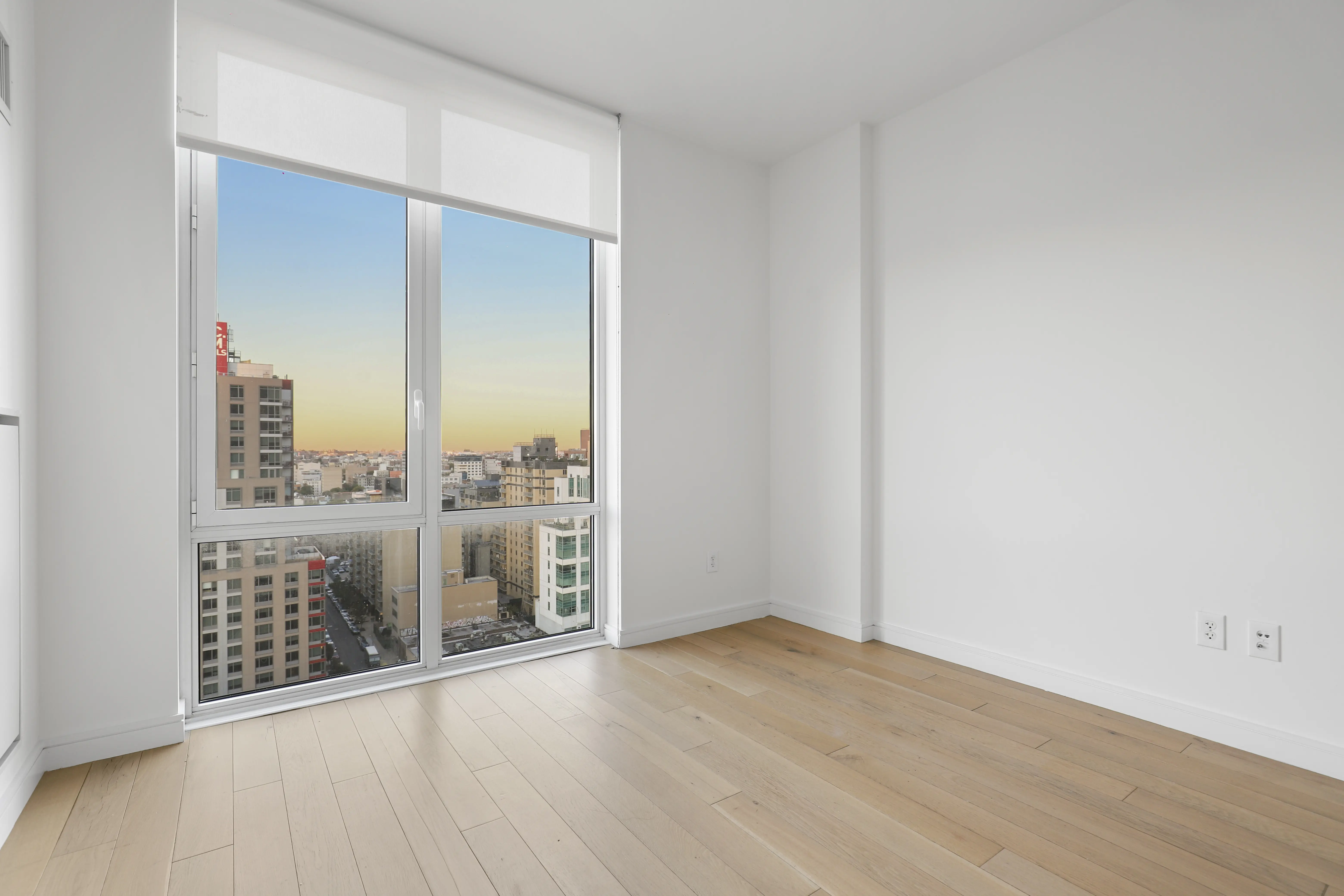 An empty room featuring large windows that showcase a panoramic view of the city skyline.
