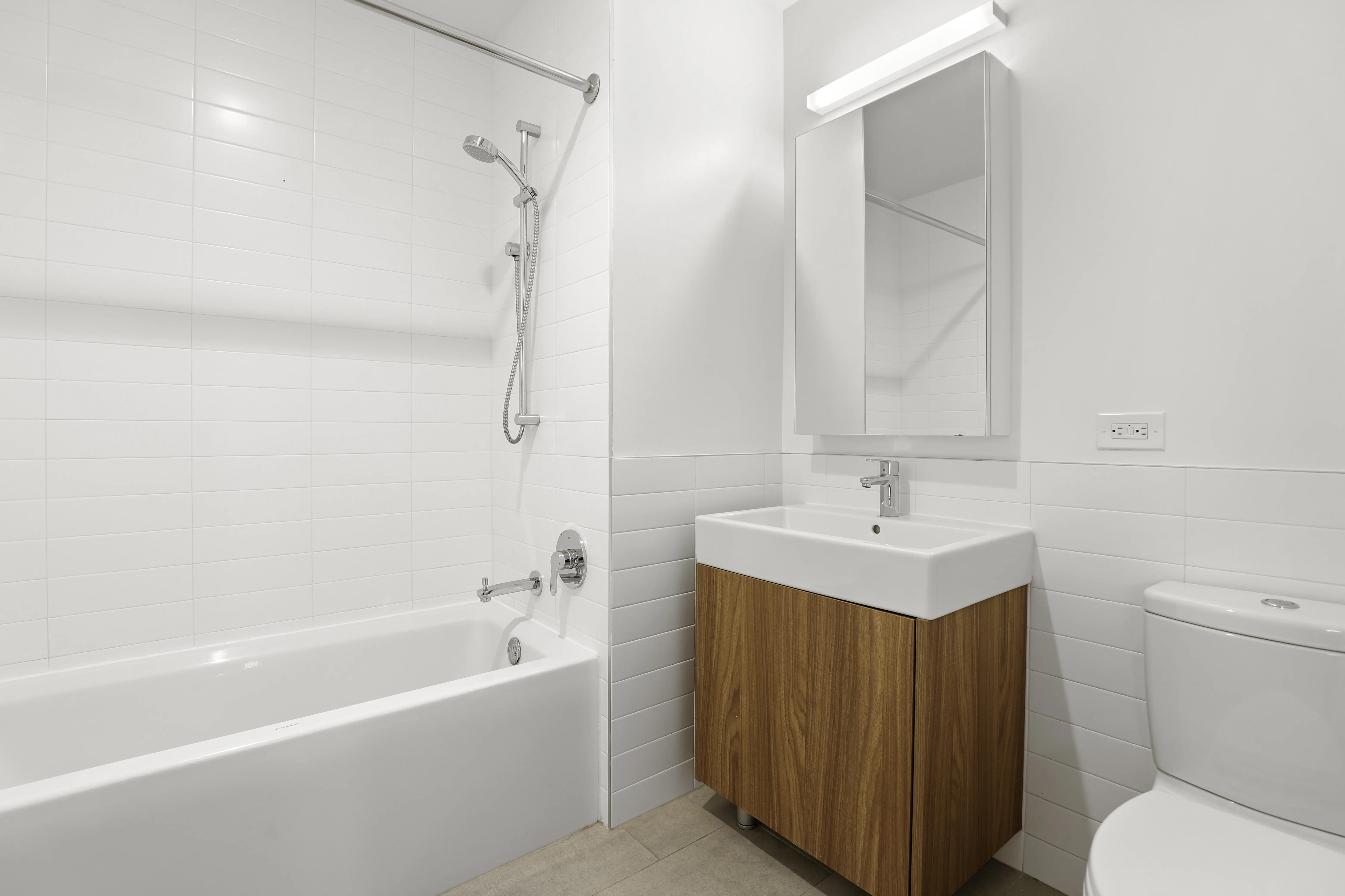 A clean bathroom featuring a white bathtub, toilet, and sink against a neutral backdrop.