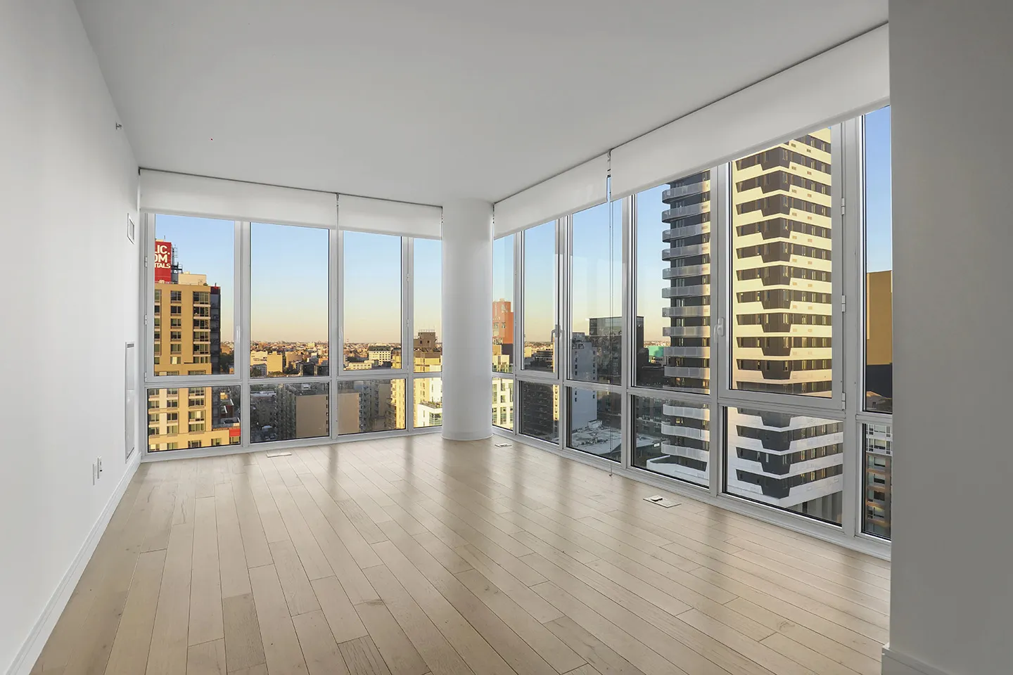 A spacious empty room featuring hardwood floors and large windows allowing natural light to fill the space.