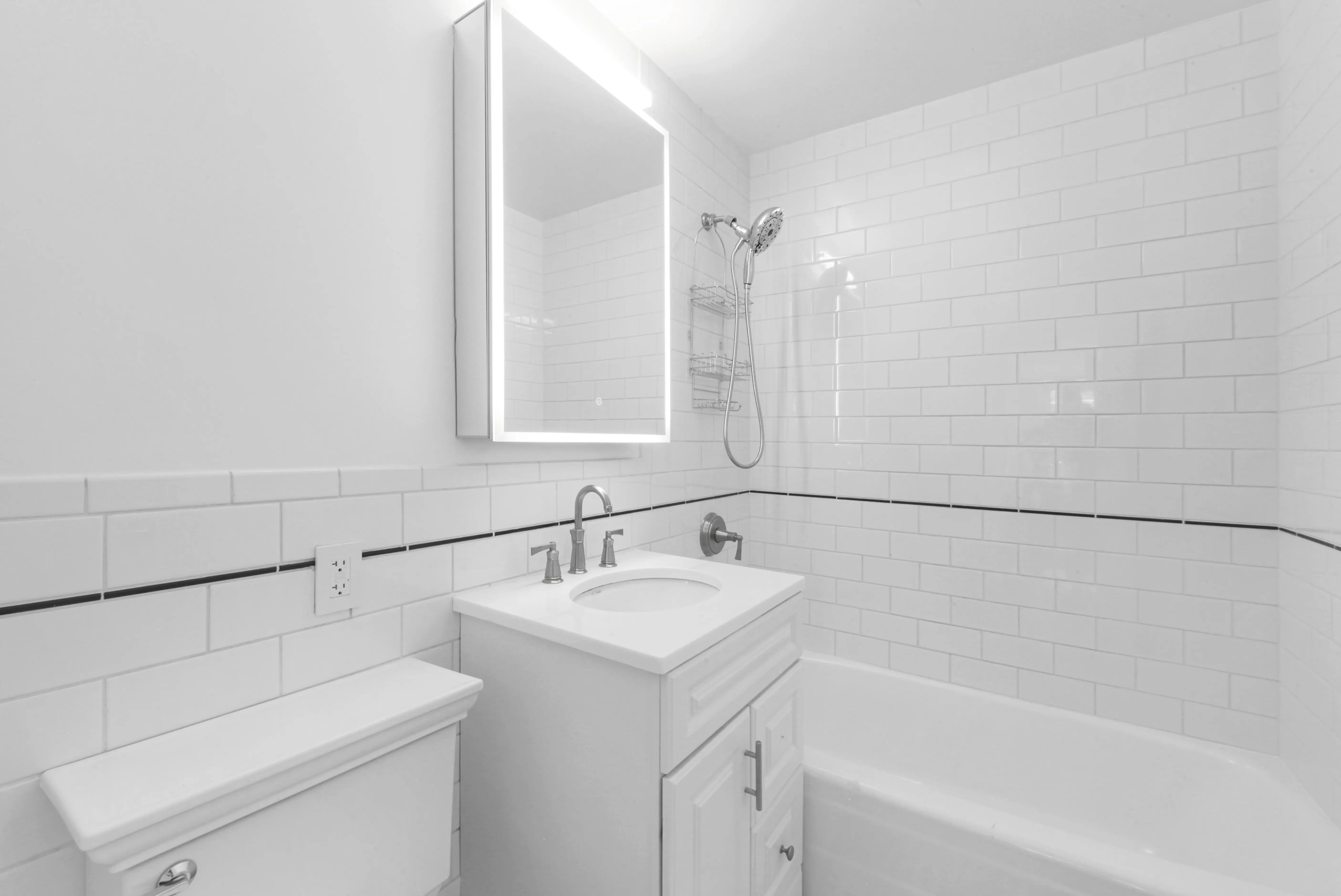 A clean white bathroom featuring a sink, toilet, and shower, showcasing a modern and minimalist design.
