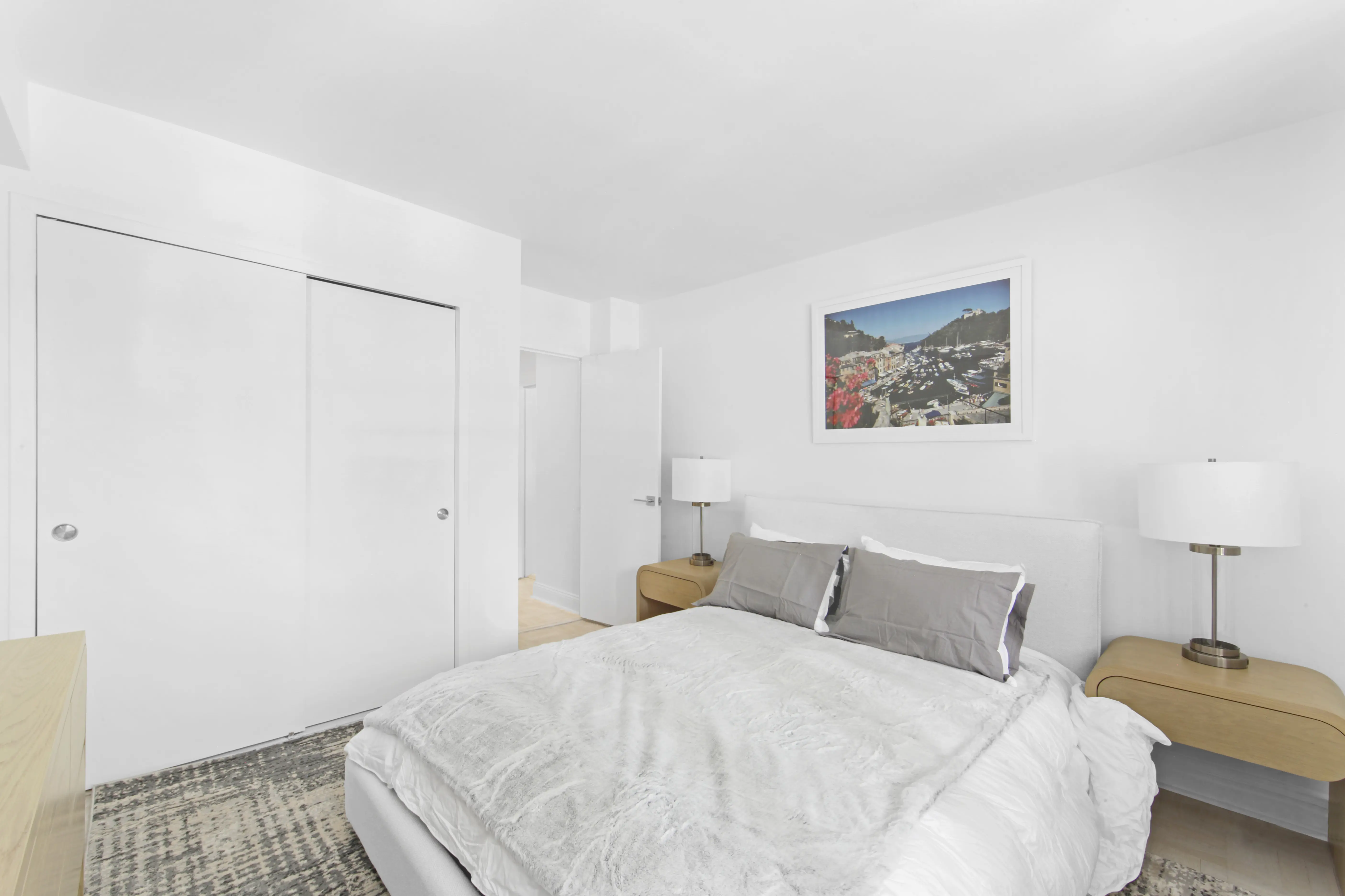 A simple bedroom featuring white walls and a neatly made bed, creating a clean and serene atmosphere.