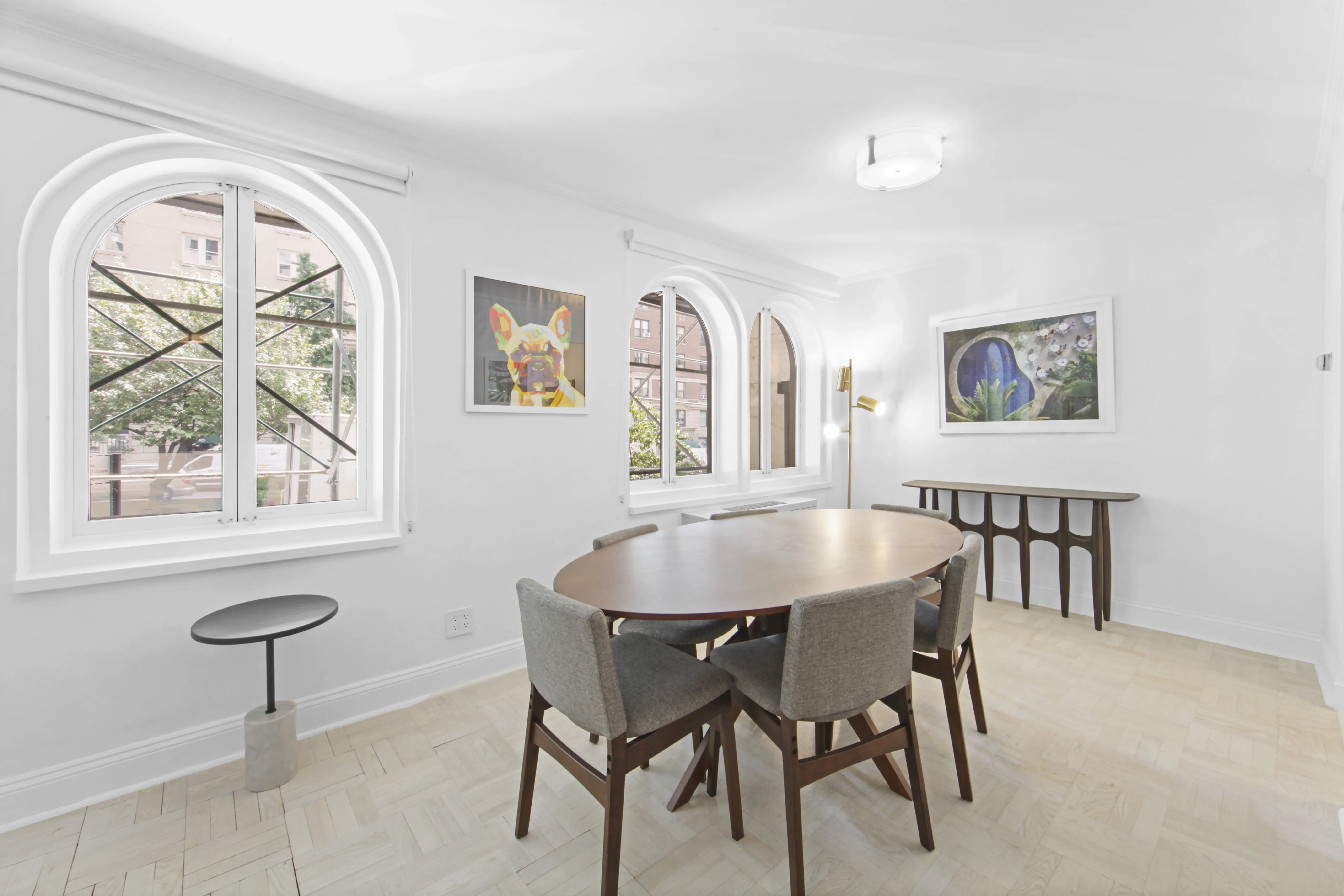 A dining room featuring a table and chairs positioned in front of a large window, allowing natural light to enter.