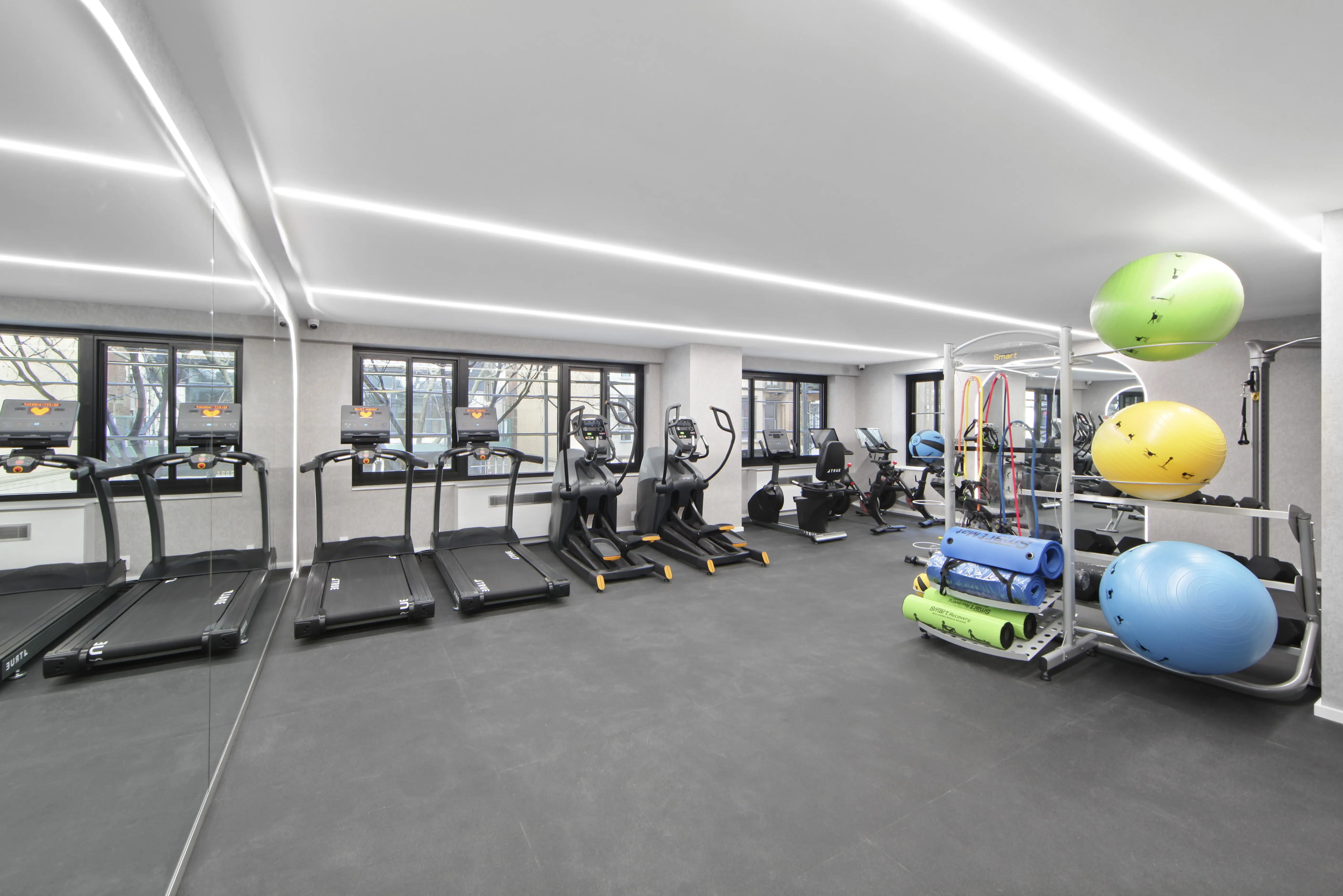 Interior of a gym with multiple treadmills and various exercise balls positioned around the space.
