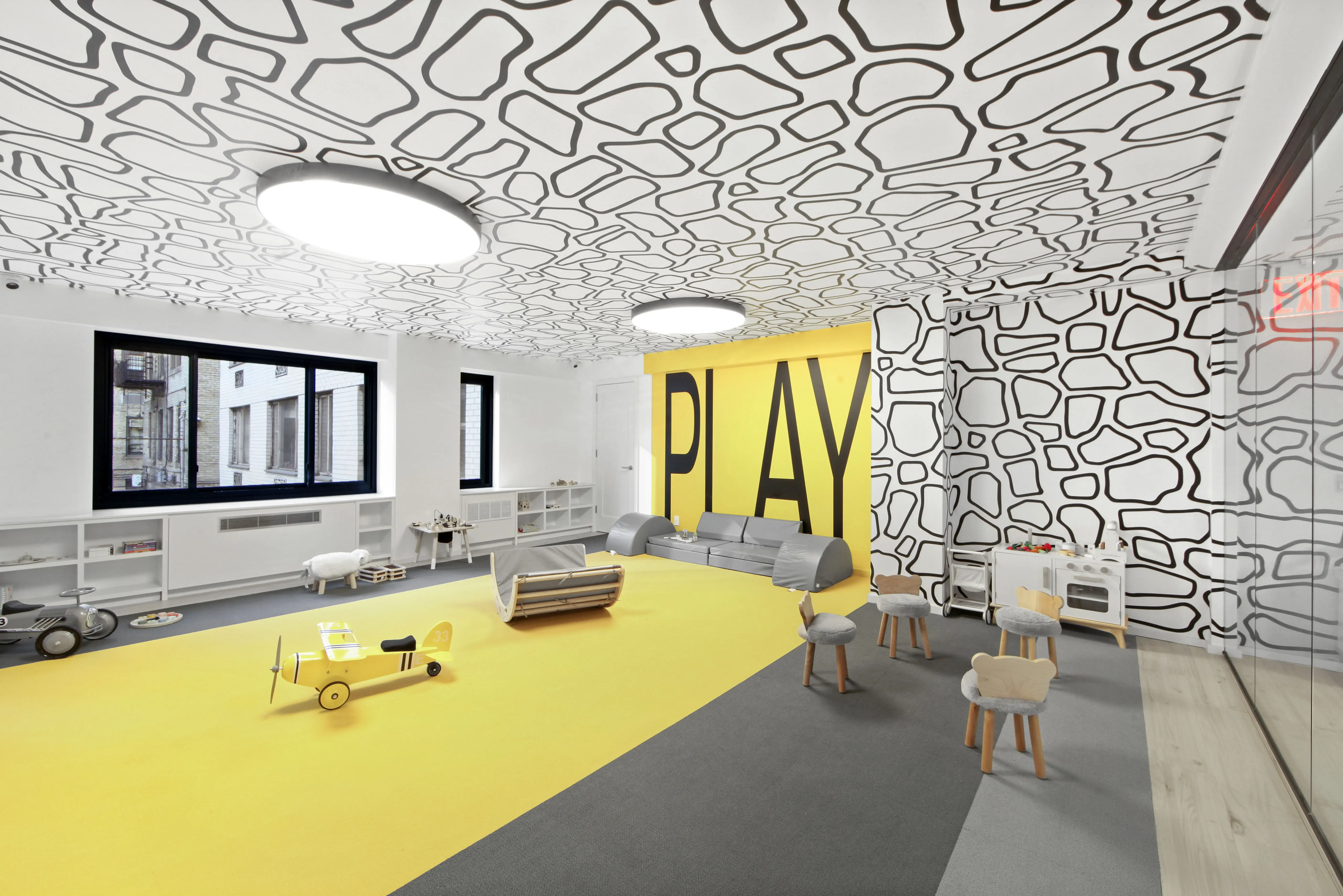 A playroom featuring yellow and black walls, complemented by a soft yellow rug on the floor.
