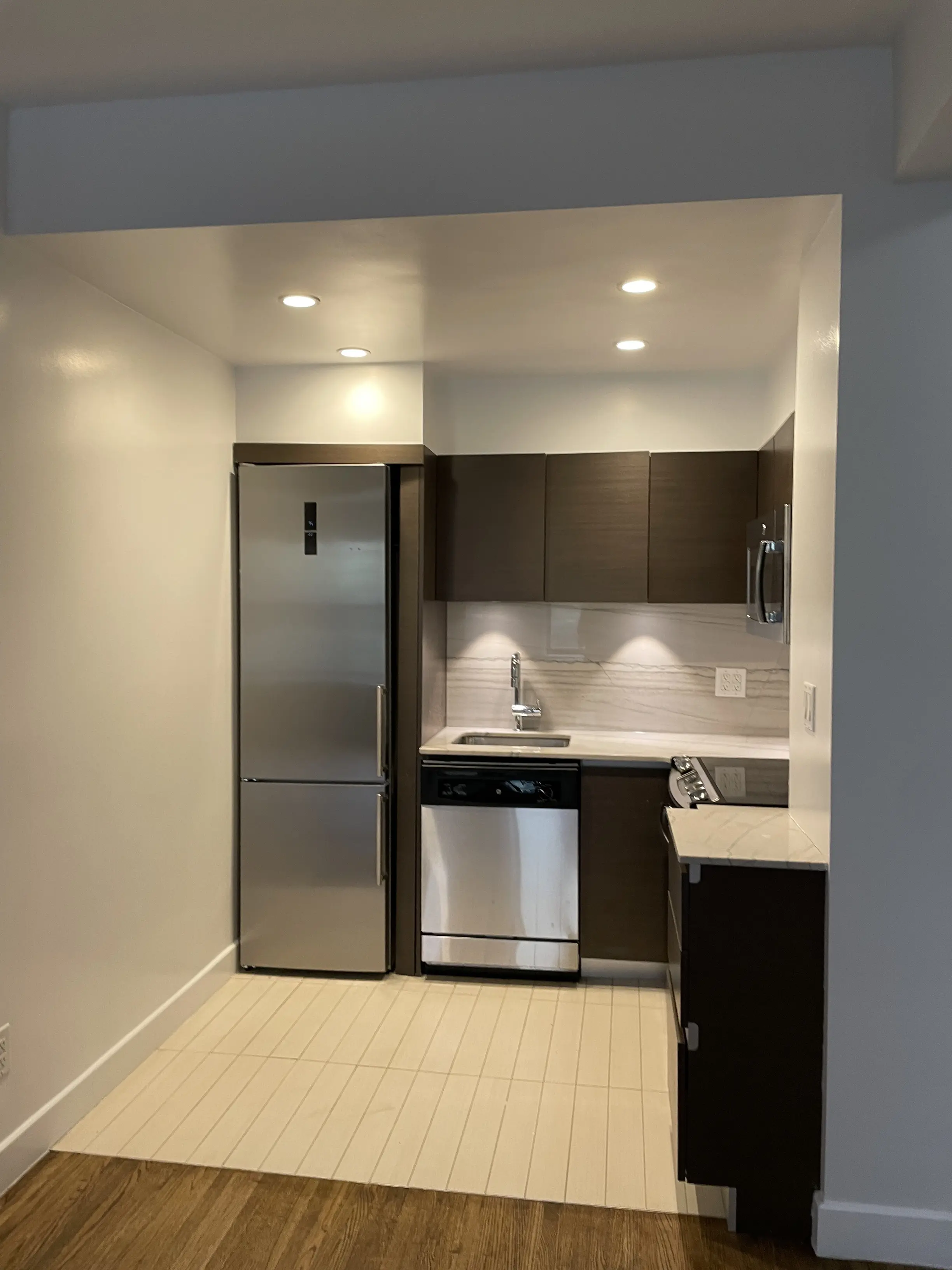 A modern kitchen featuring stainless steel appliances and warm wood floors, creating a stylish and inviting atmosphere.