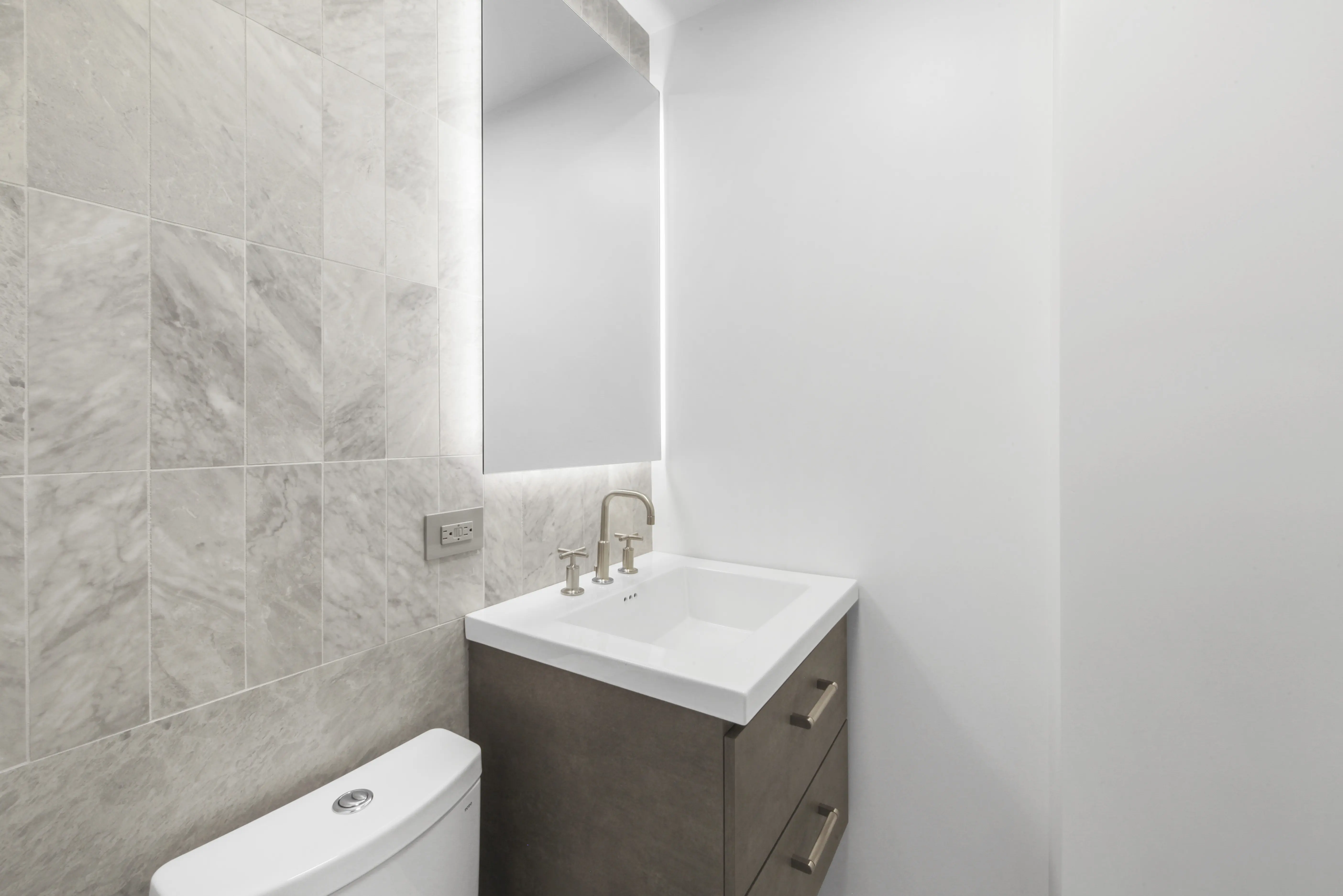 A bathroom featuring a sink, toilet, and mirror, showcasing a clean and functional design.