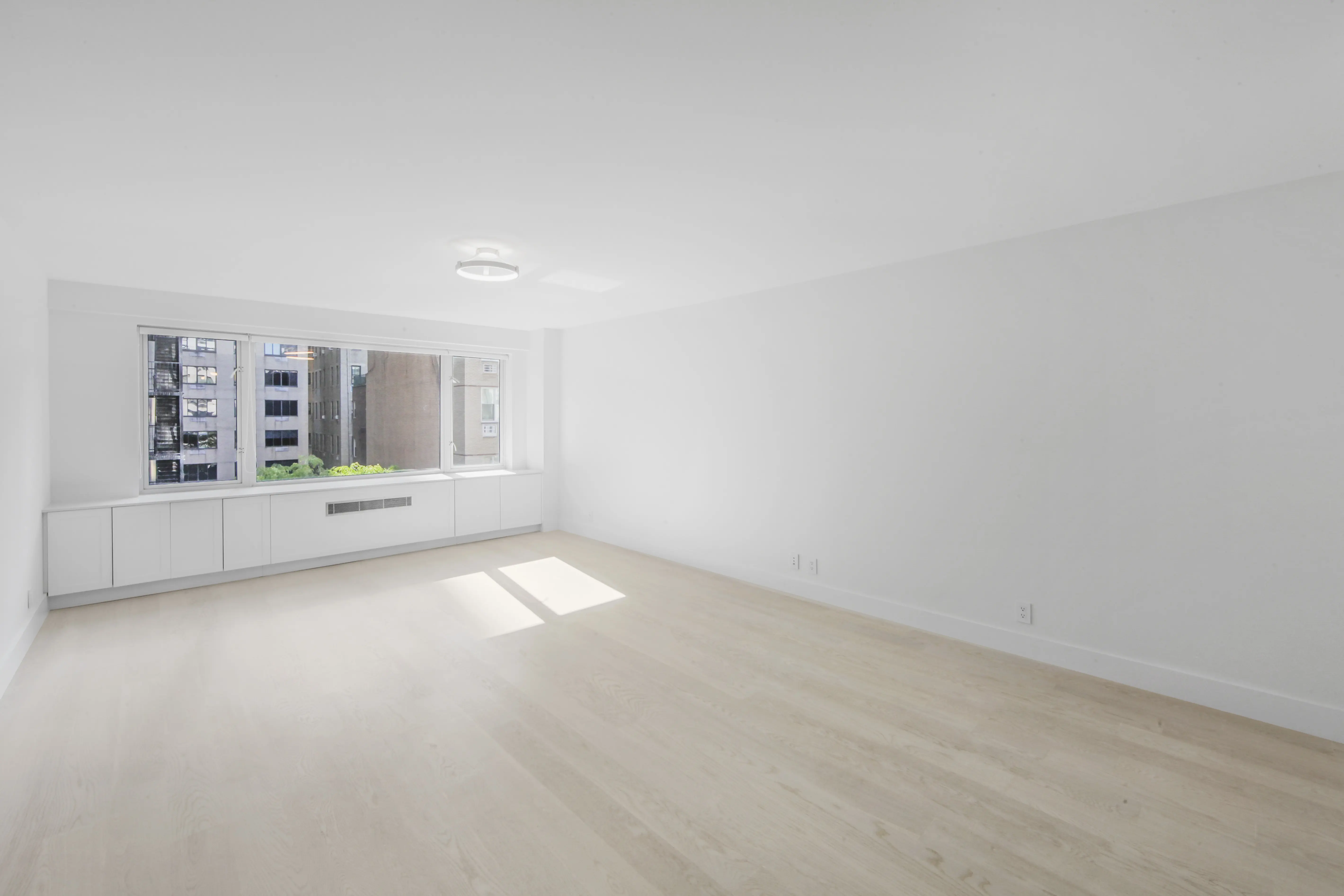 An empty room featuring white walls and polished hardwood floors, creating a bright and spacious atmosphere.