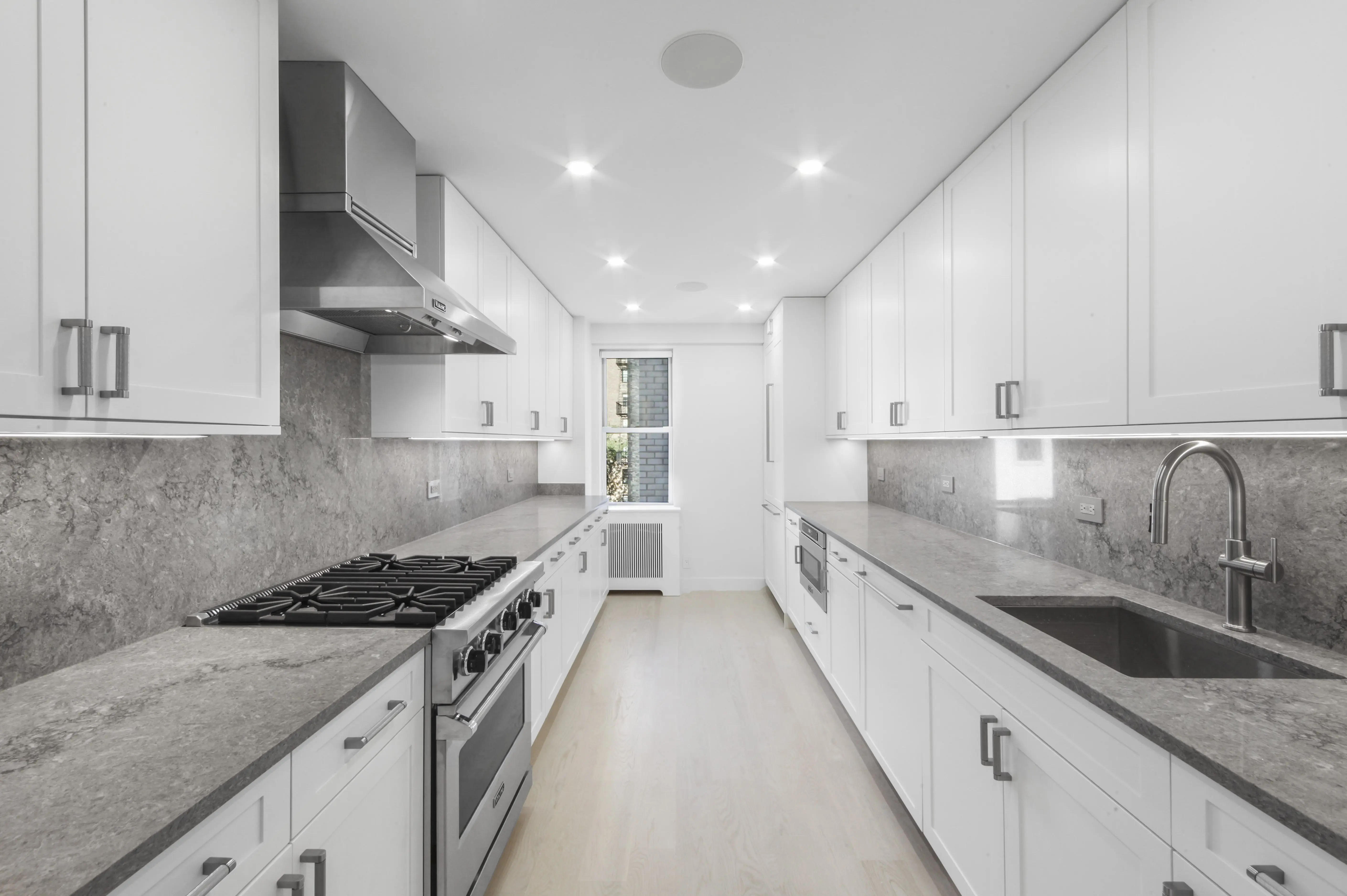 A spacious white kitchen featuring modern stainless steel appliances and ample counter space.