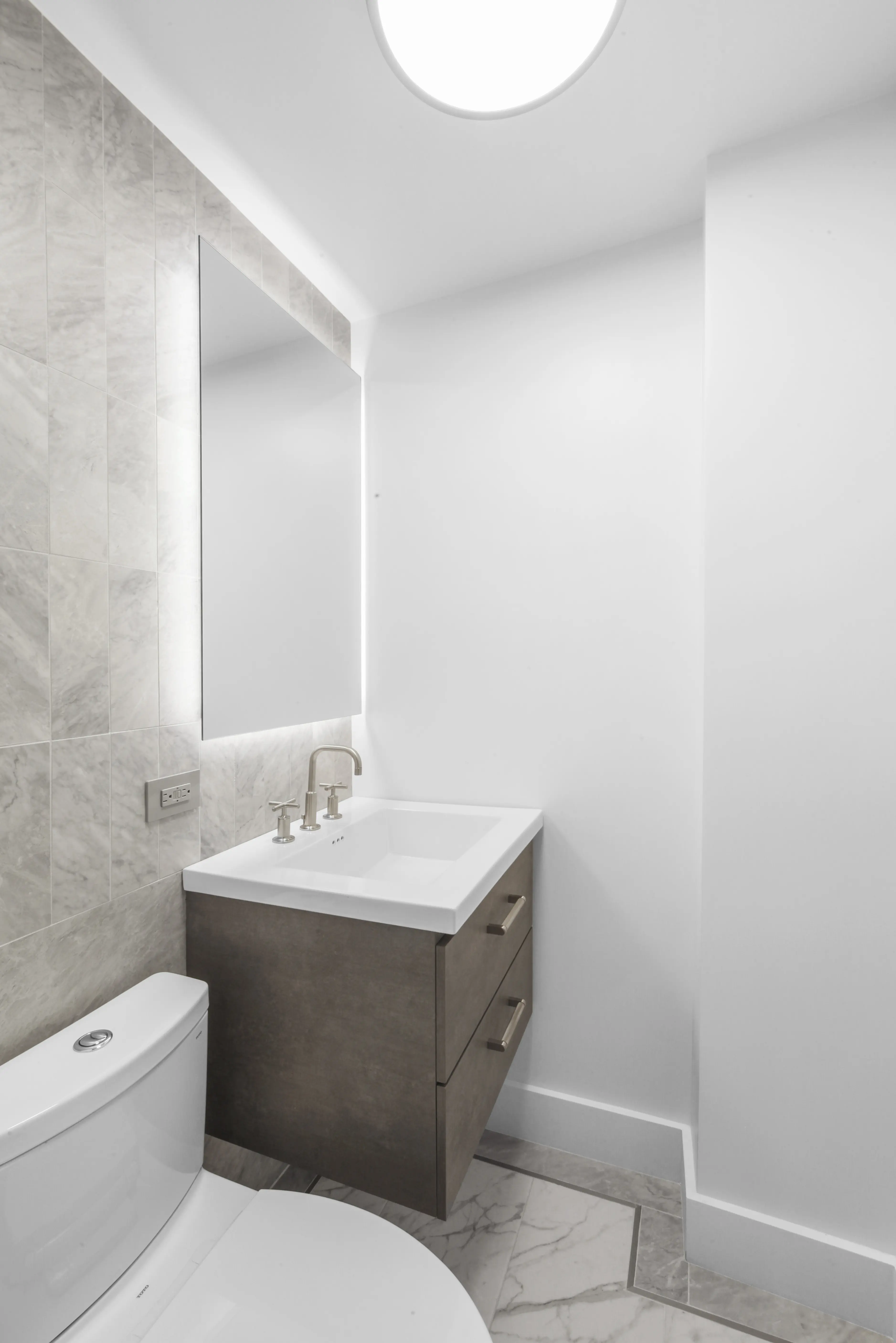 A well-lit bathroom with a sink, toilet, and mirror, emphasizing a tidy and organized space.