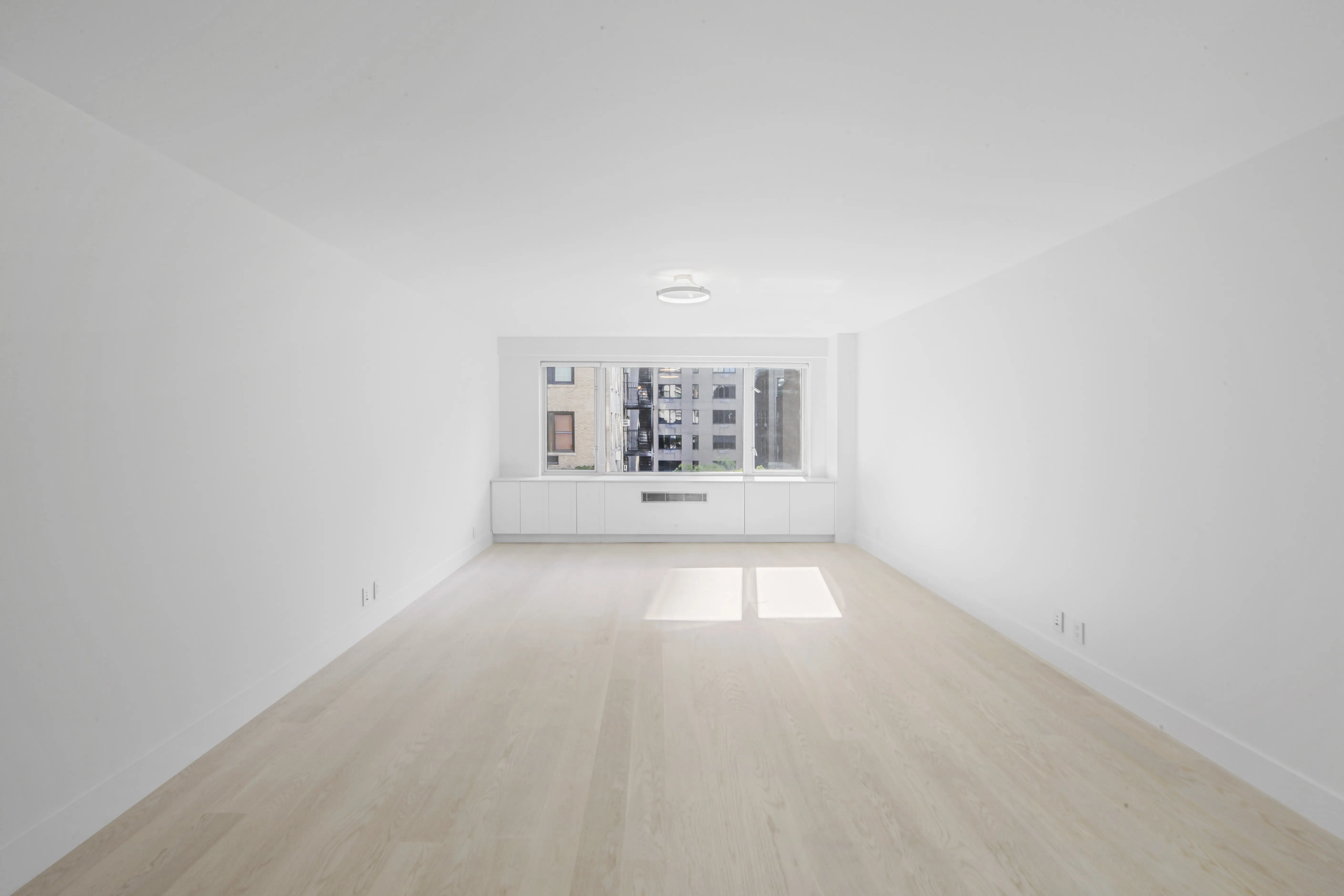 A vacant room with clean white walls and smooth hardwood flooring, emphasizing simplicity and openness.