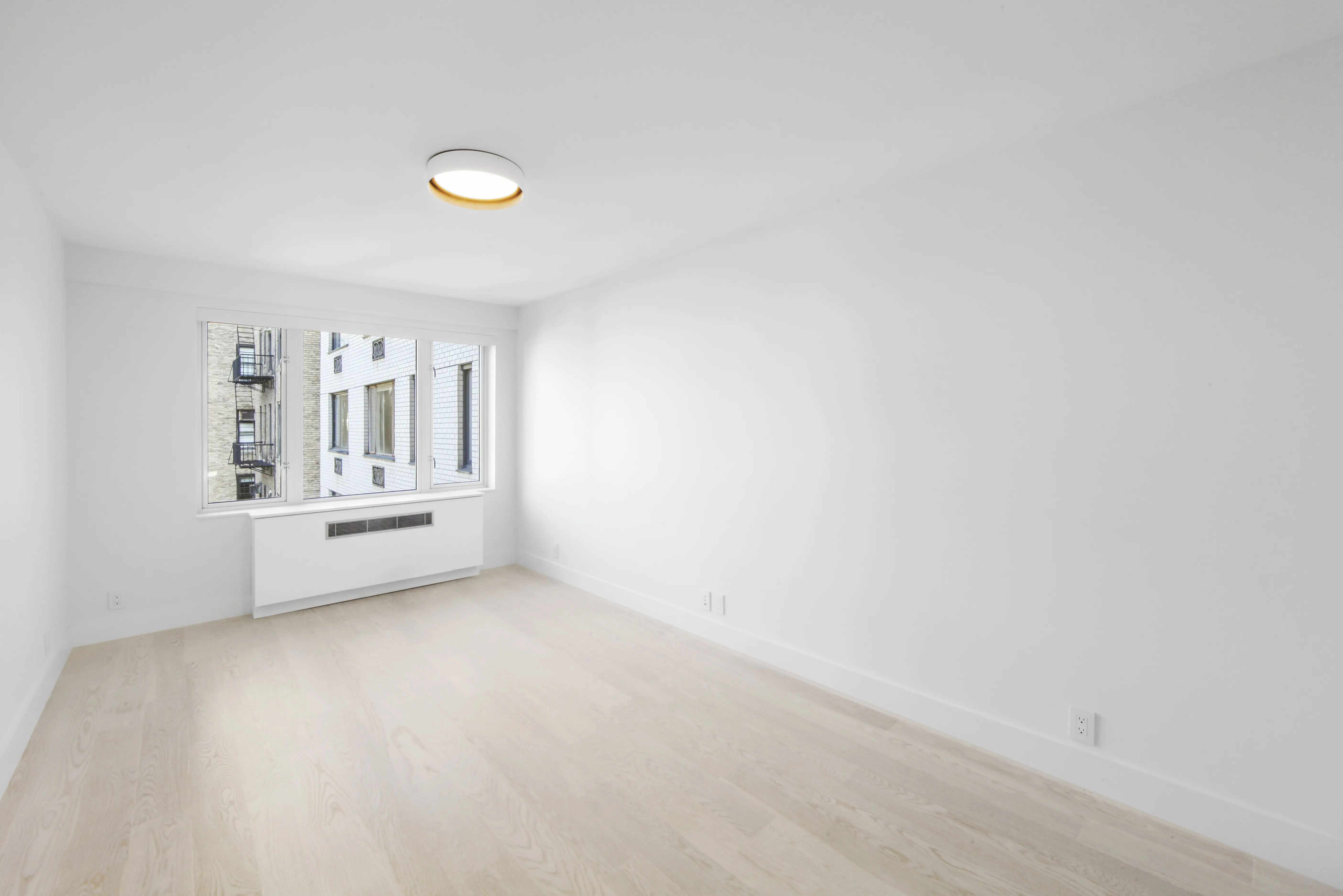 An unoccupied room showcasing white walls and hardwood floors, offering a minimalist and airy environment.