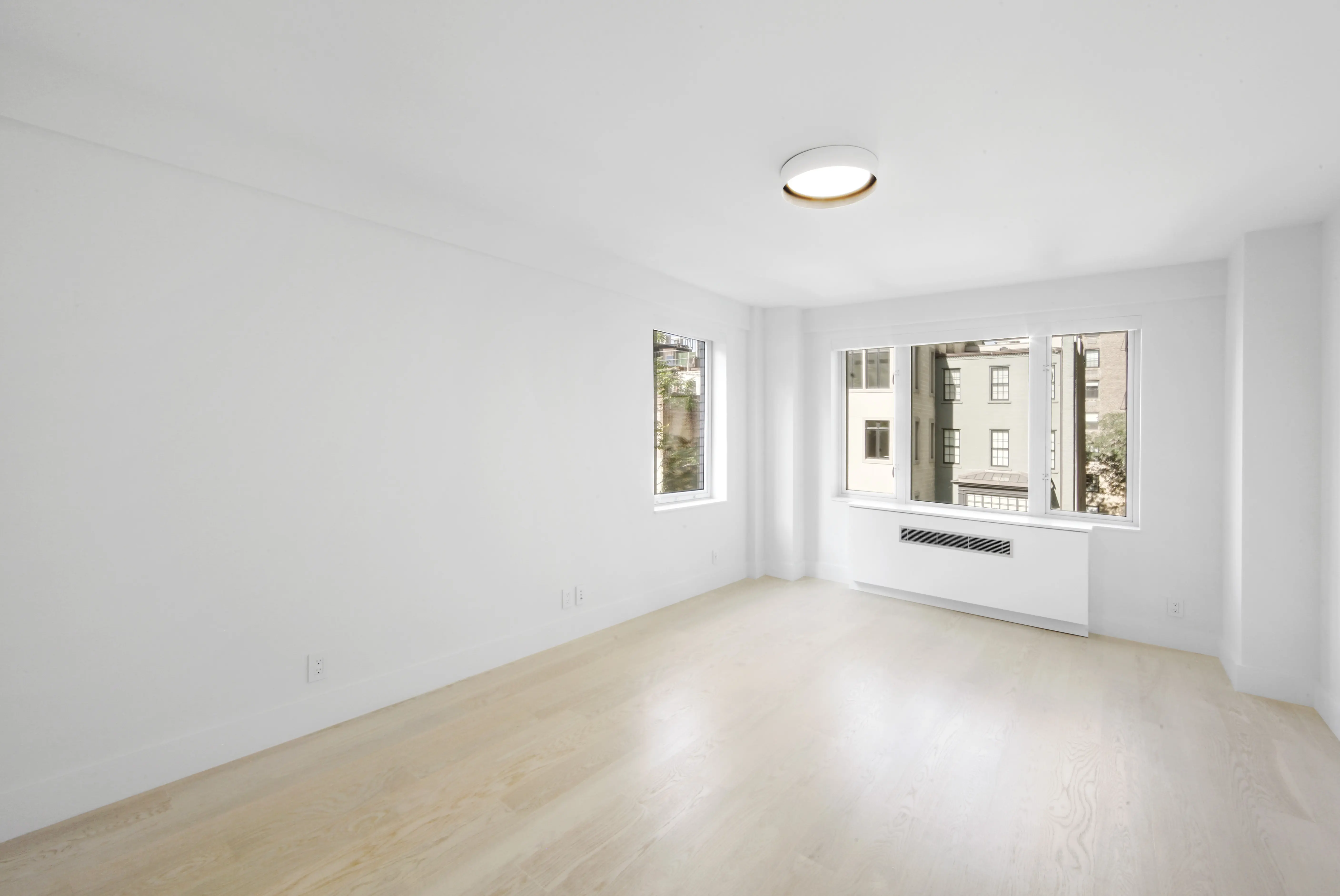 An unoccupied room showcasing white walls and warm hardwood floors, emphasizing simplicity and openness.